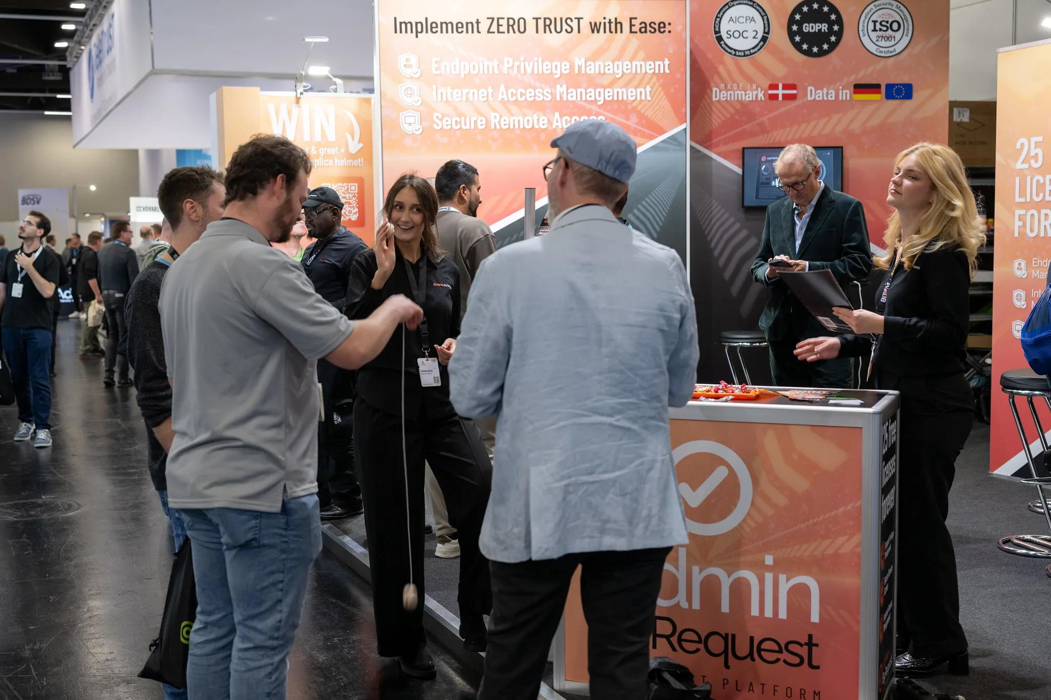 Belebter Admin By Request-Messestand mit Besuchern und Zero-Trust-Signage auf der it-sa Nürnberg.