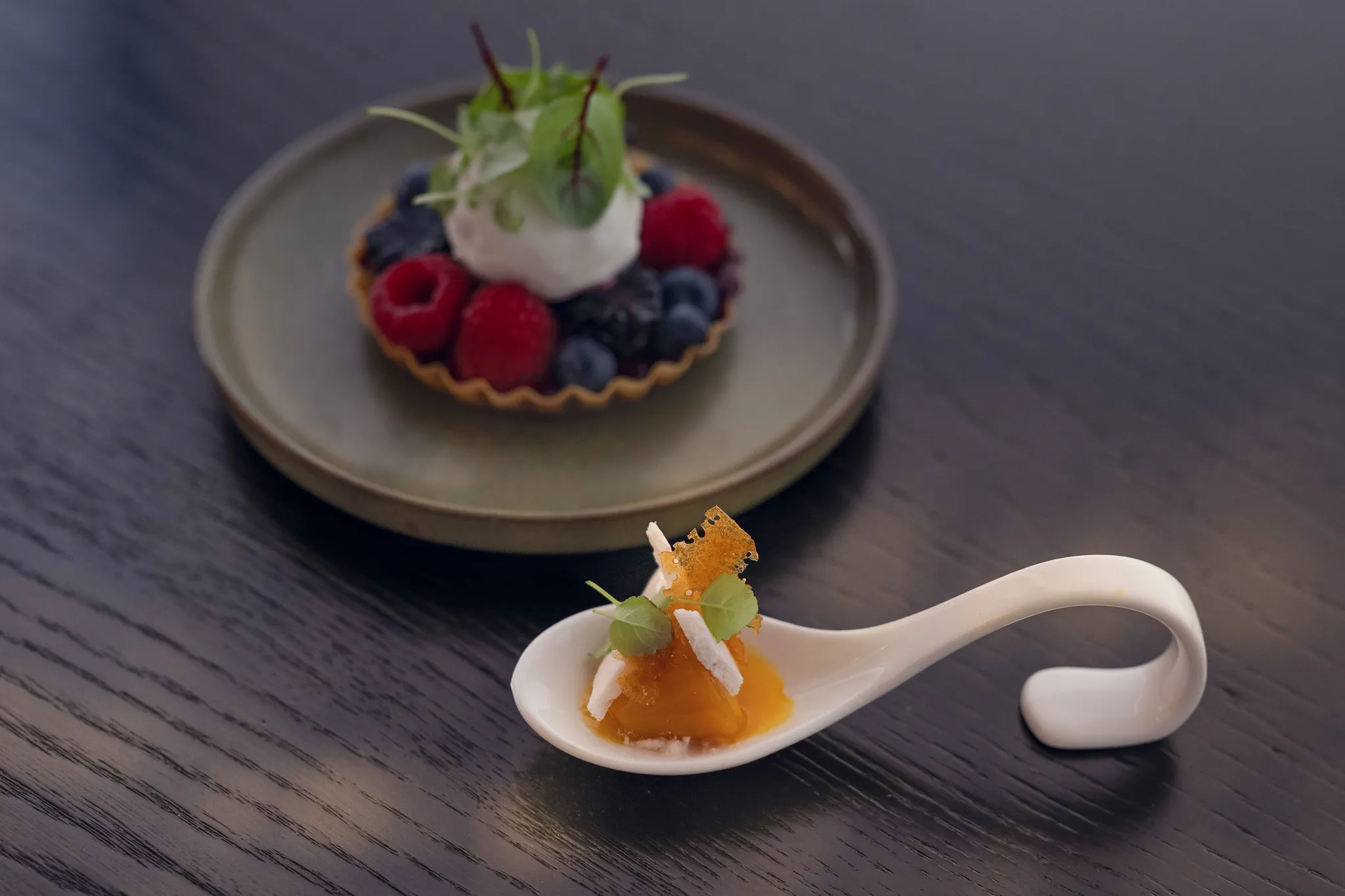 Amuse-Bouche auf Porzellanlöffel mit Mangogel und Karamellchip, Fine-Dining-Fotografie Nürnberg.