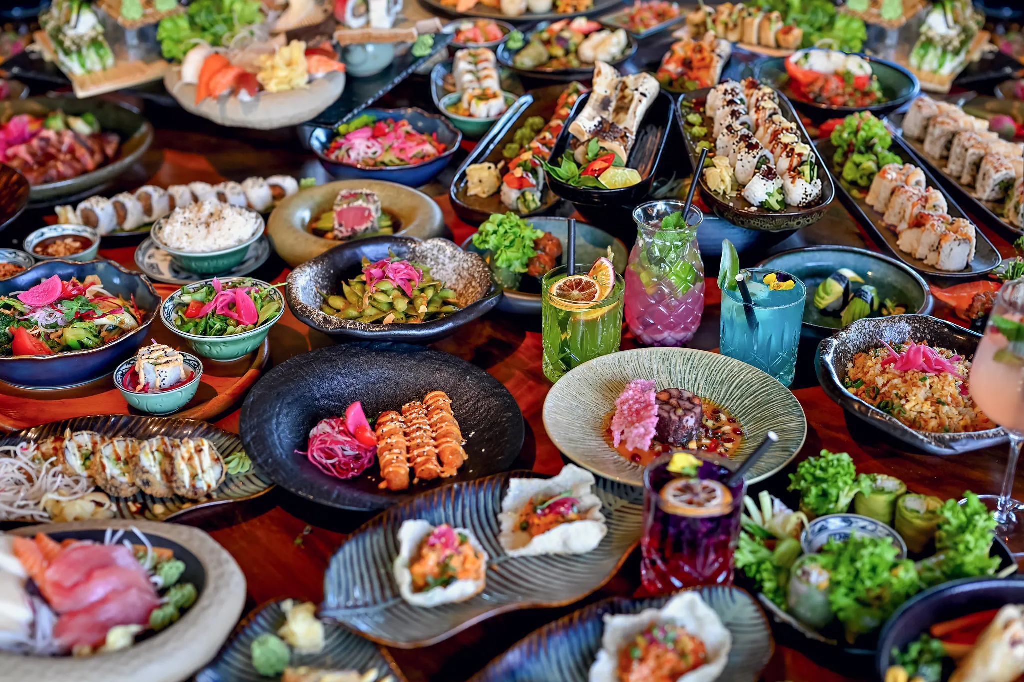 Asiatisch gedeckter Tisch mit Sushi, Salaten und Cocktails, Gastronomie-Fotografie.