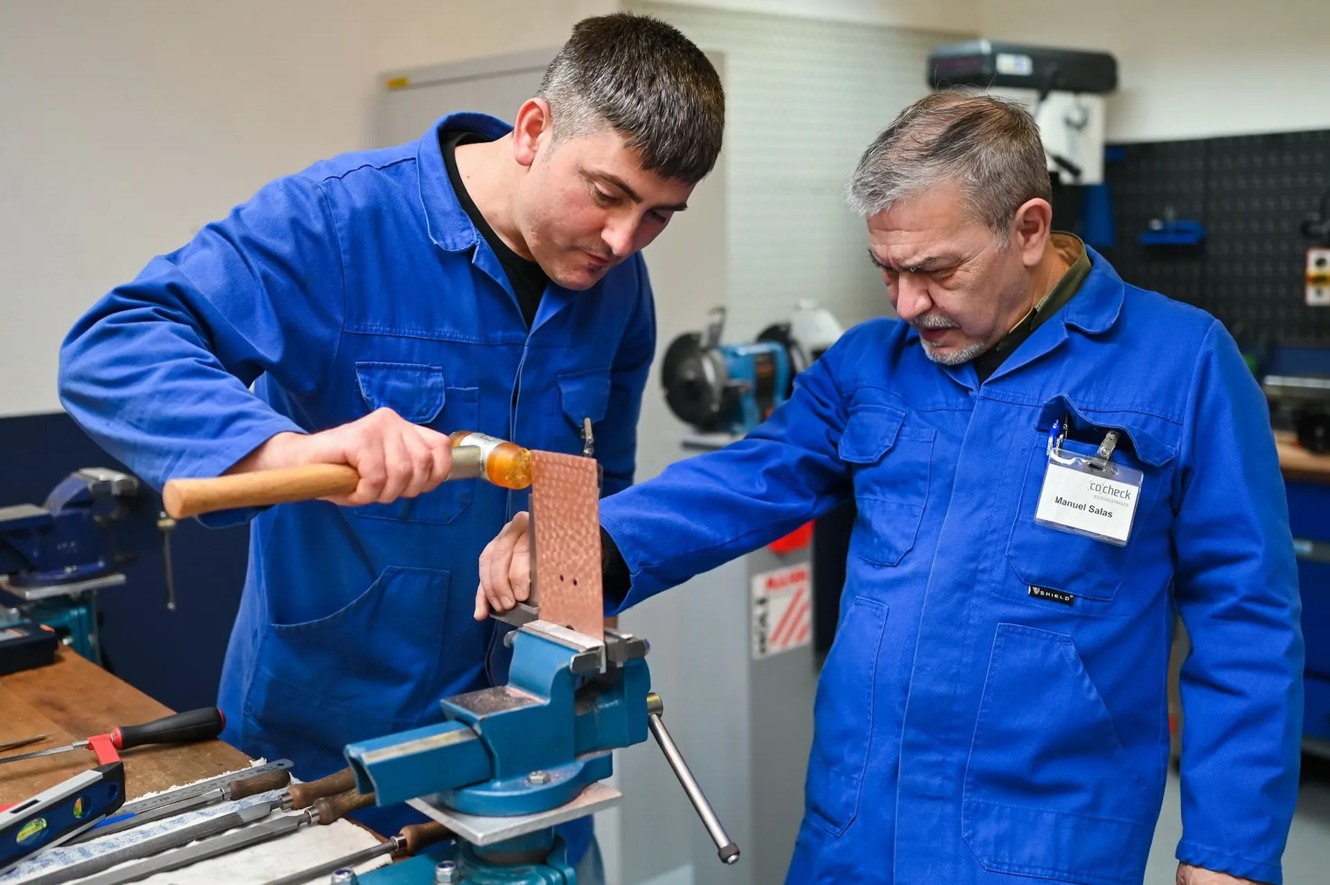 Auszubildender im Metallberuf mit Hammer, authentische Momentaufnahme aus der Unternehmensfotografie.