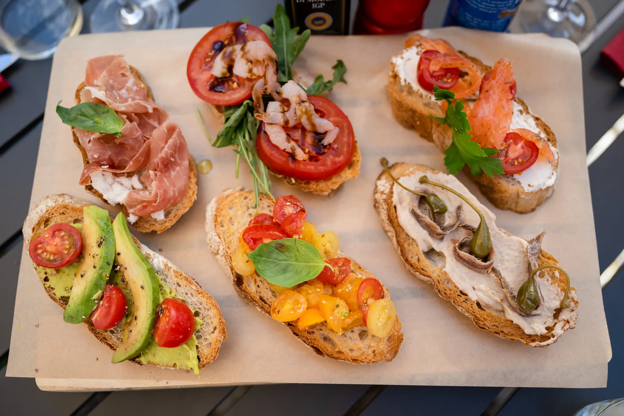 Bruschetta-Variation mit Prosciutto, Lachs und Avocado auf Holzbrett.