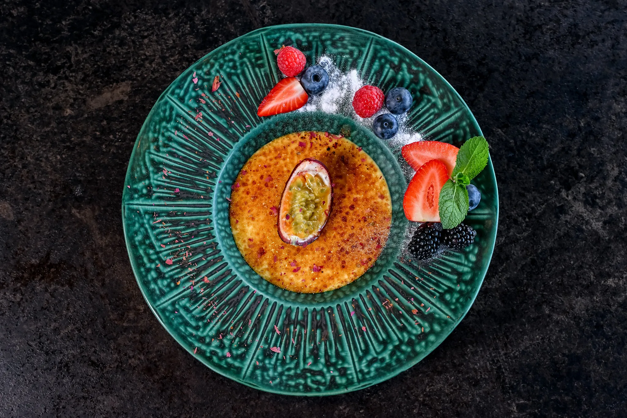 Crème brûlée mit Passionsfrucht, Erdbeeren, Blaubeeren und Minze.