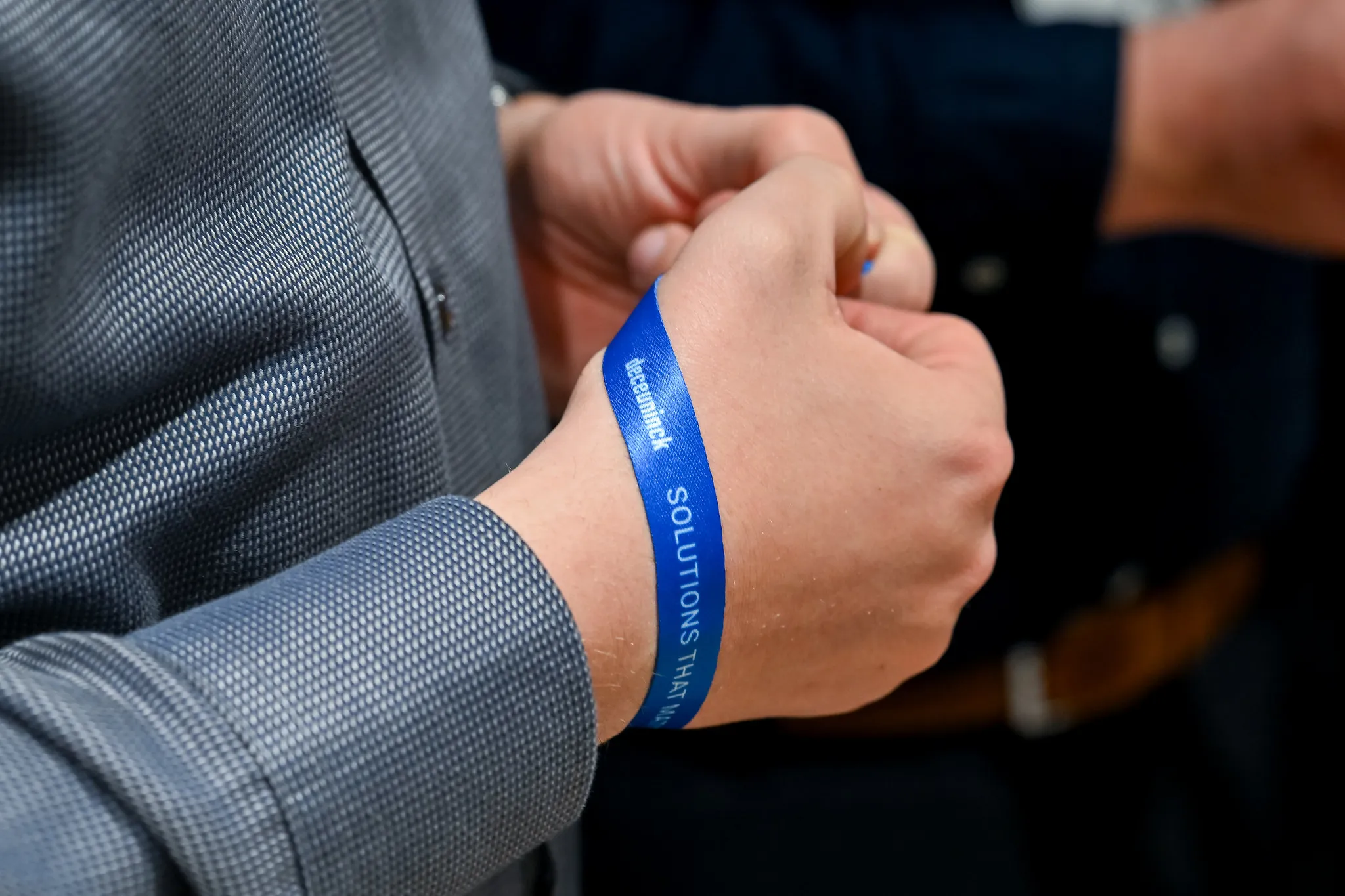 Nahaufnahme eines gebrandeten Deceuninck-Armbands am Handgelenk auf der Messe.