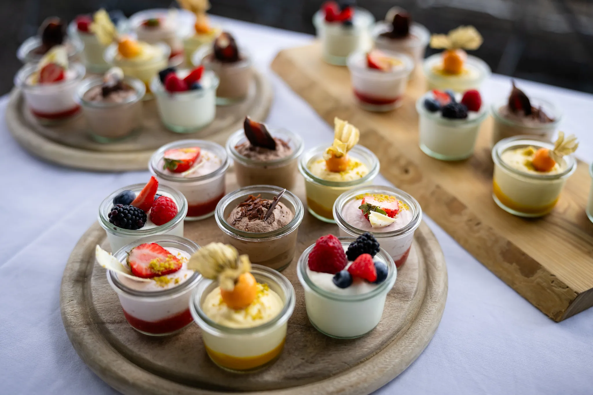 Dessertbuffet mit kleinen Mousse-Gläsern und frischen Beeren, Gastronomie-Fotografie.