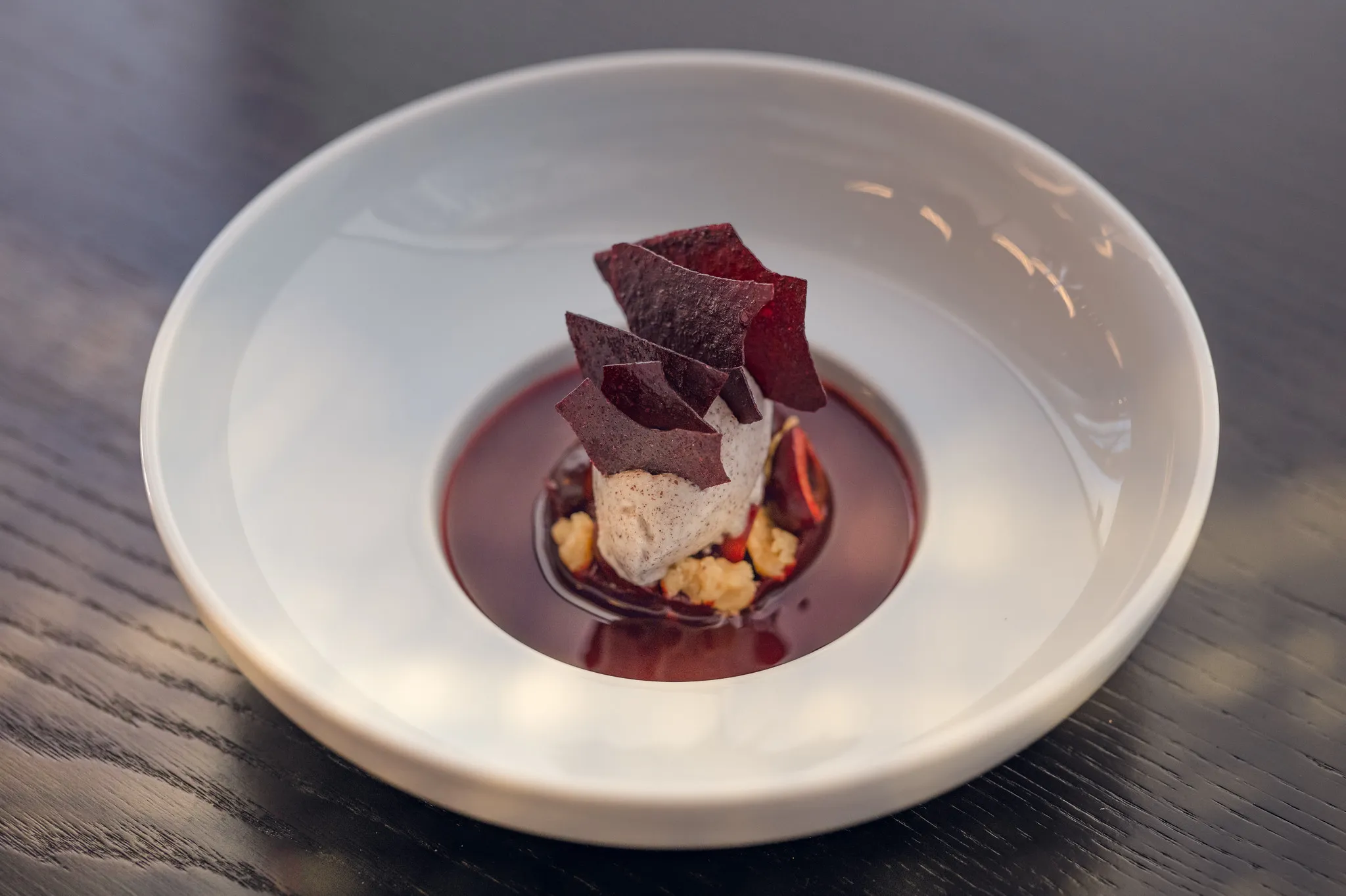 Dessert mit cremiger Nocke, Fruchtchips und Streuseln in Rotweinsud, Dessert-Fotografie Nürnberg.