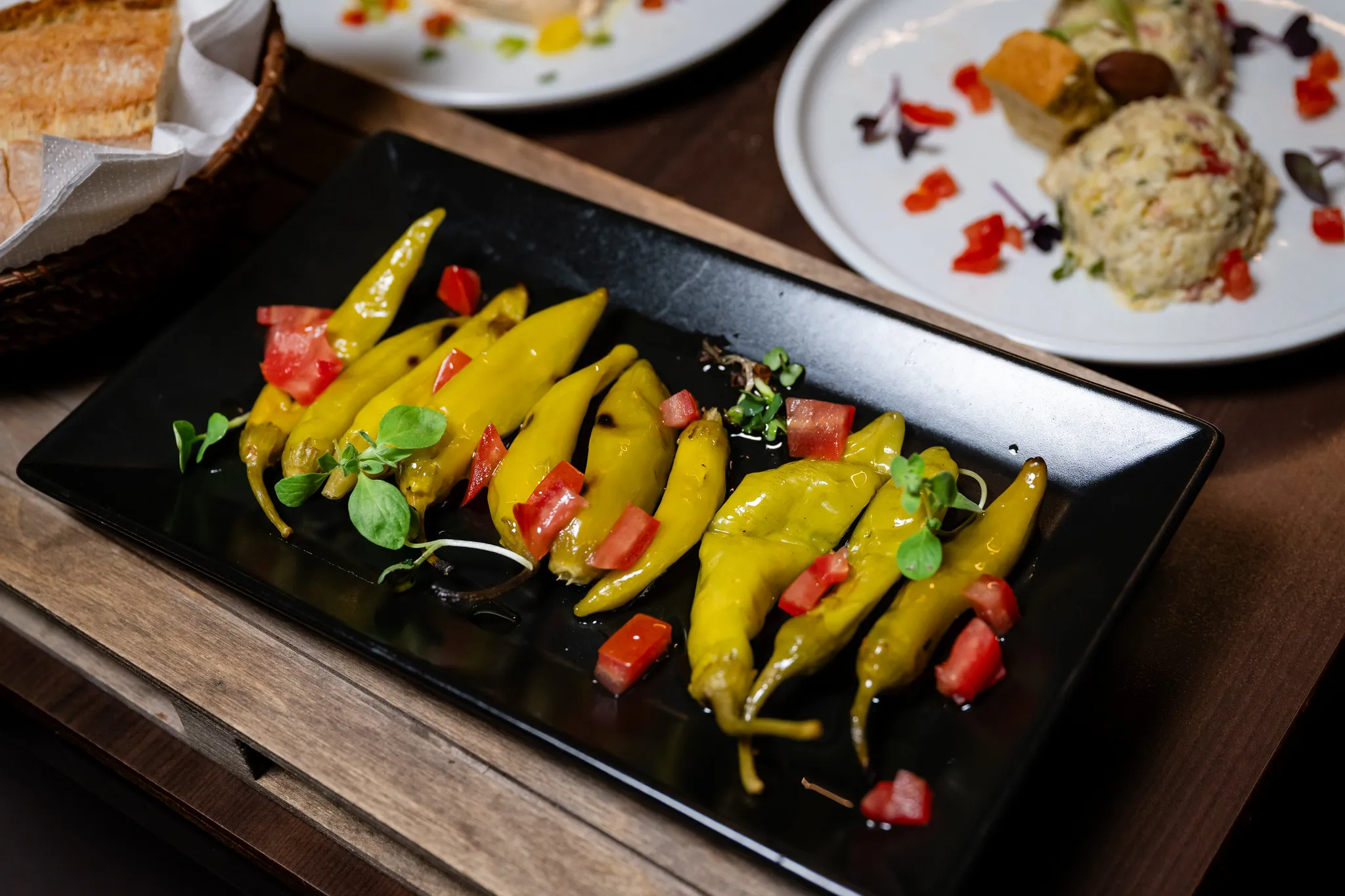 Eingelegte grüne Peperoni mit Tomaten, mediterrane Vorspeise der Gastronomie-Fotografie.