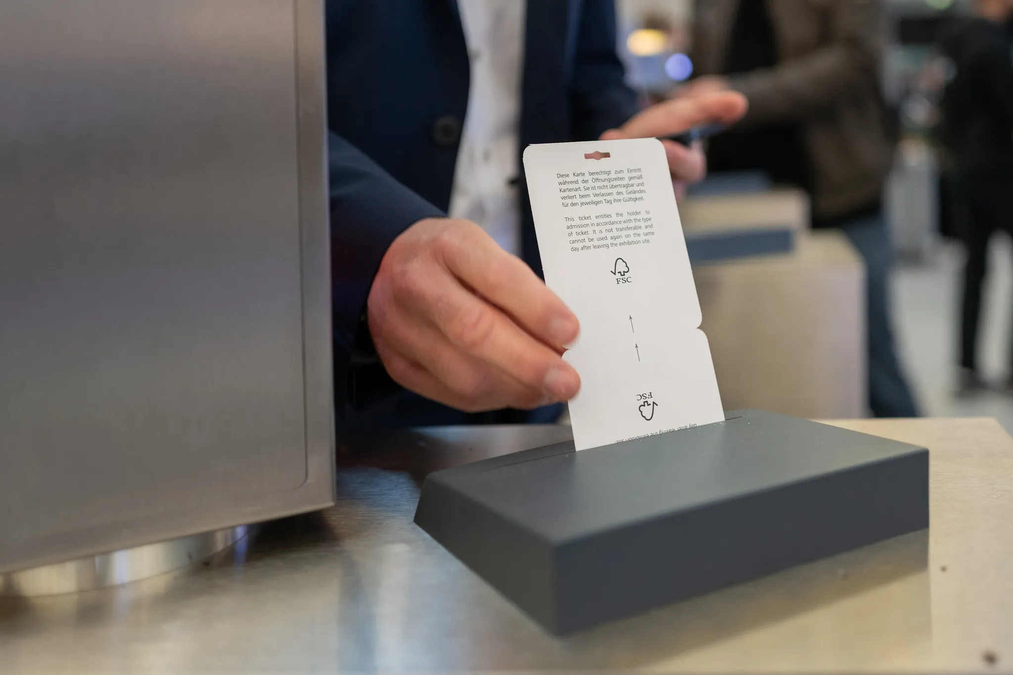 Hand steckt Einlassticket in das Kontrollsystem am Eingang der NürnbergMesse.