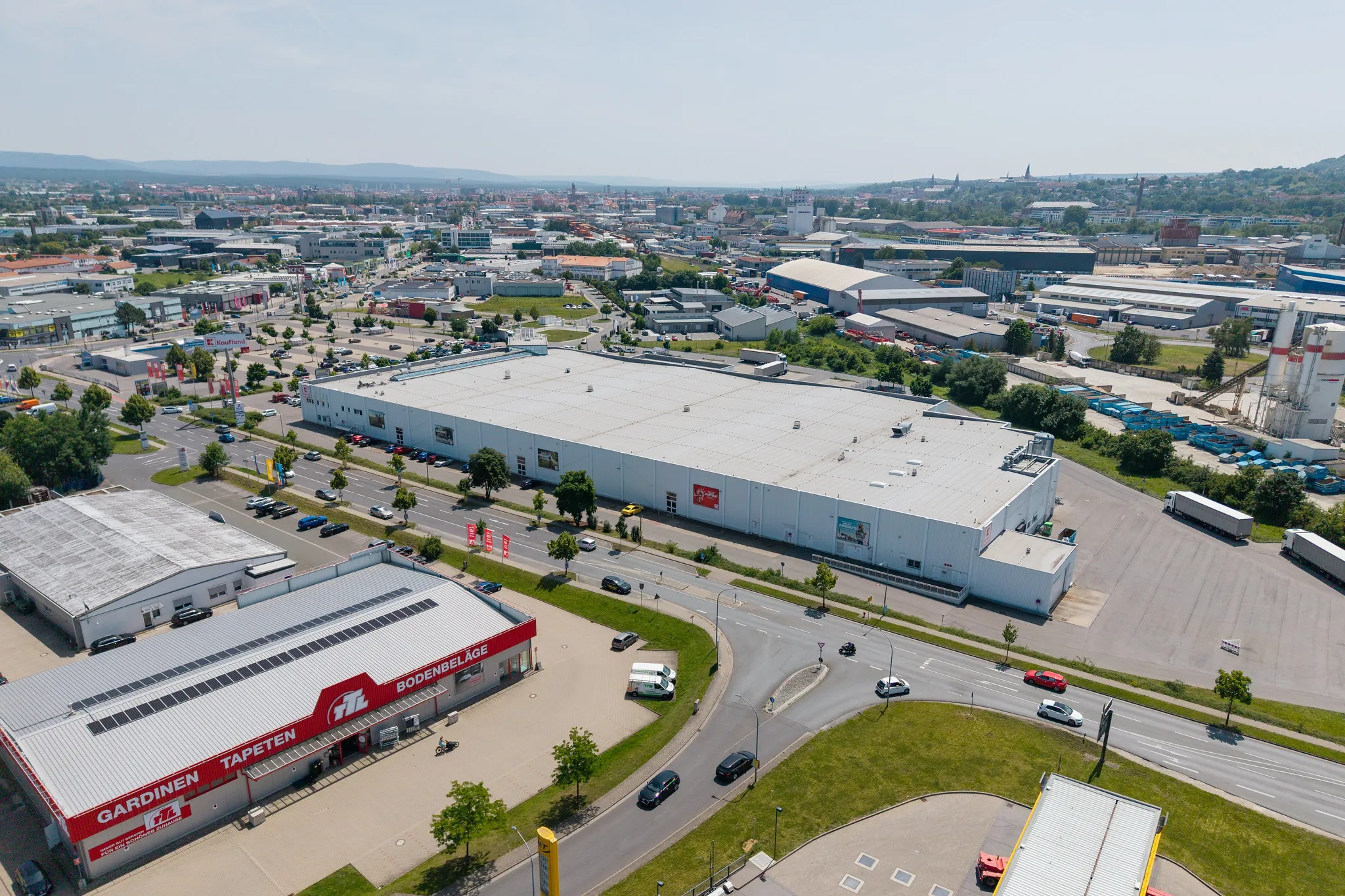 Luftaufnahme eines Fachmarktzentrums mit Innenstadt-Panorama im Hintergrund