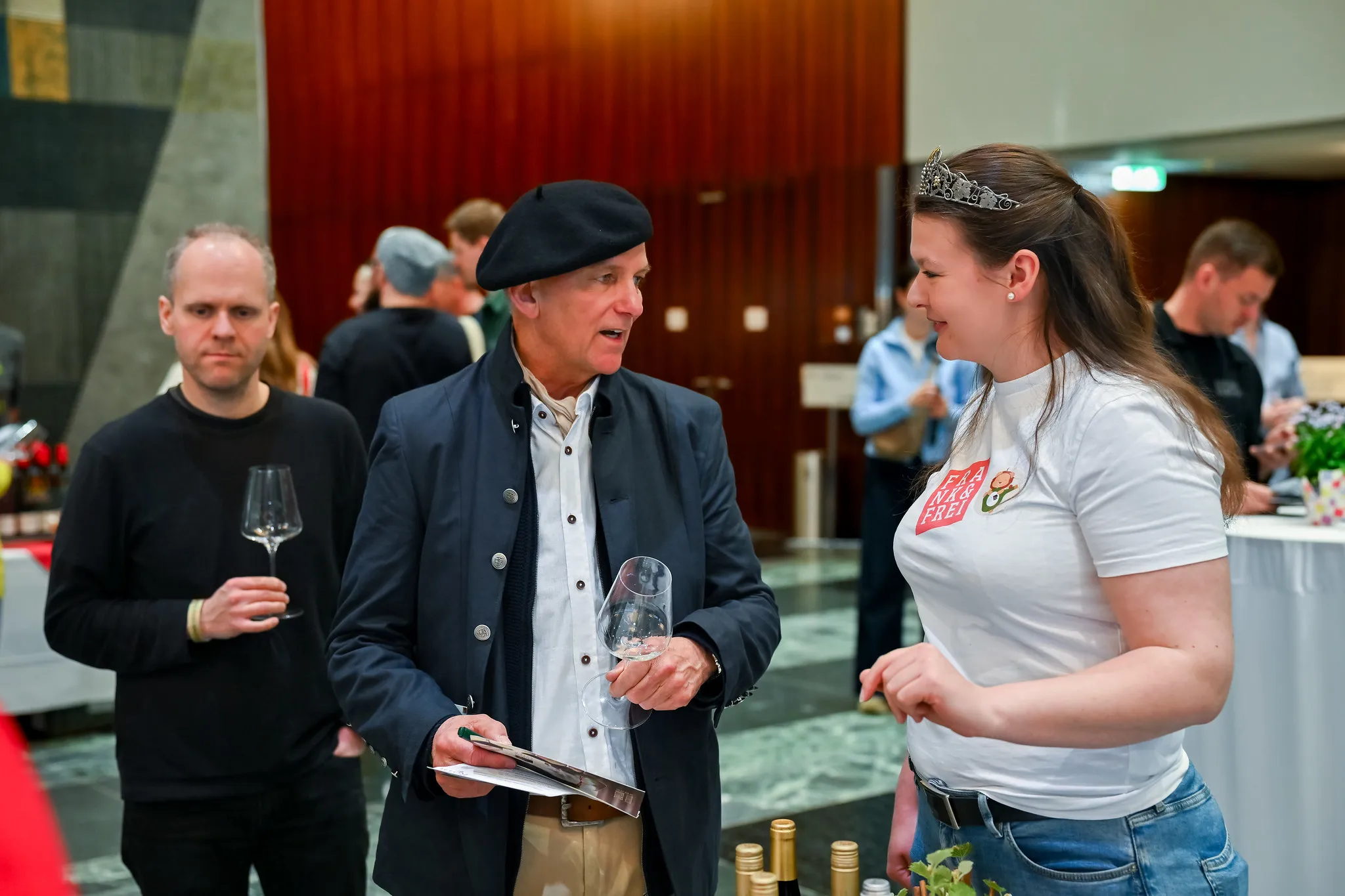 Gespräch bei Weinmesse, Eventkönigin berät Besucher am Stand