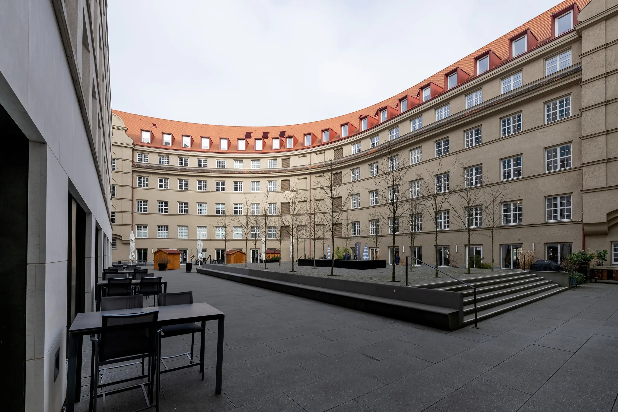 Halbrunder Innenhof mit historischer Fassade und roten Dachgauben.