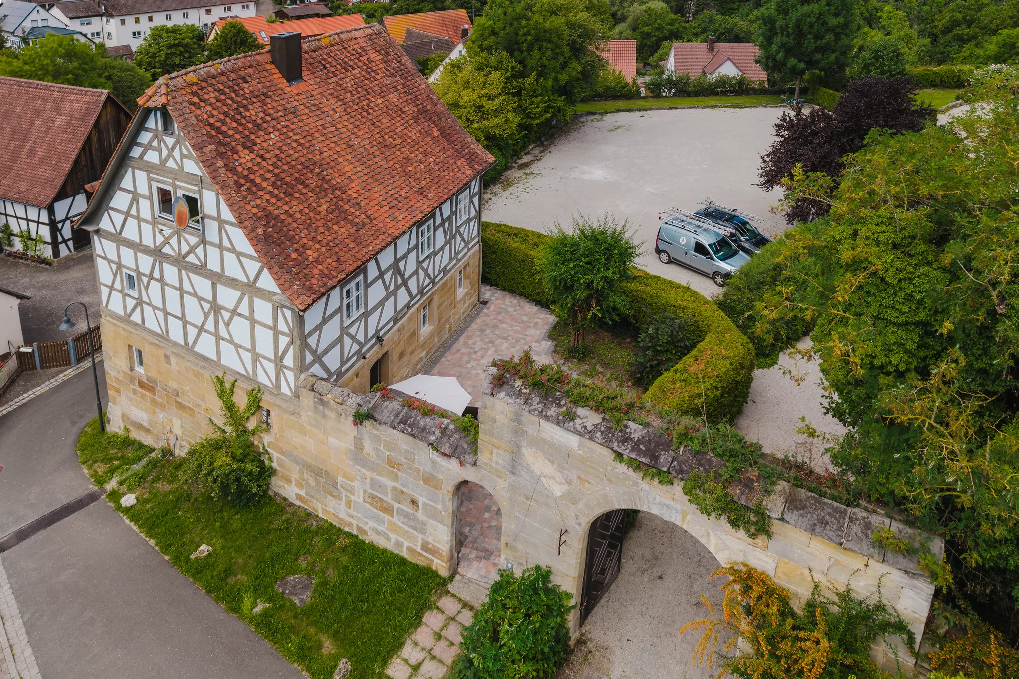 Luftaufnahme eines historischen Fachwerkhauses mit Sandstein-Torbogen und Hof
