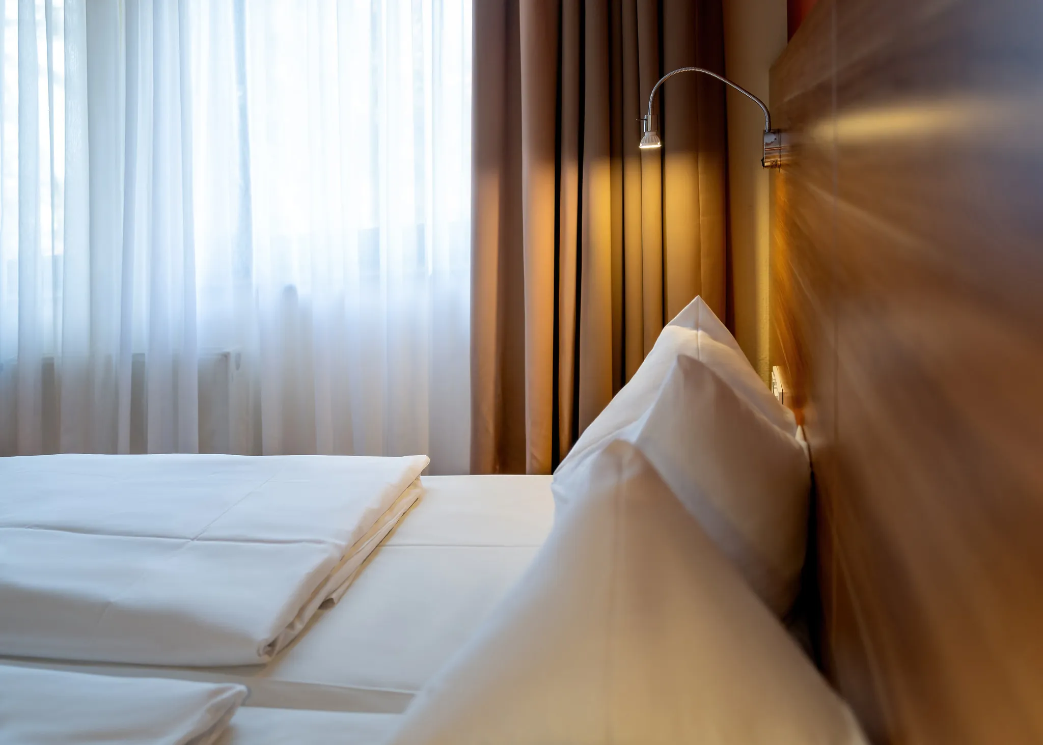 Nahaufnahme eines Hotelbetts mit weißem Kissen und eleganter Leselampe, Schlafkomfort der Hotelfotografie