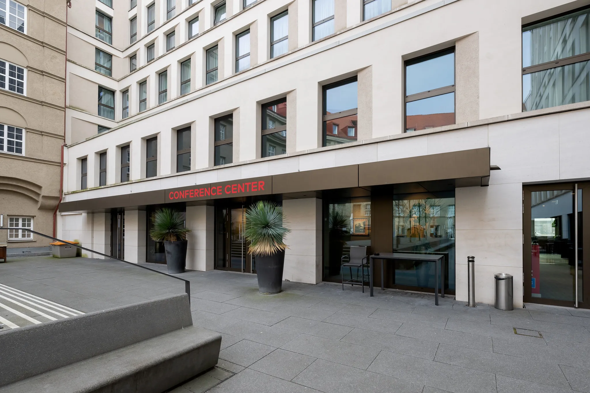 Eingang zum Hotelkonferenzzentrum mit Glasfront und dekorativen Palmen