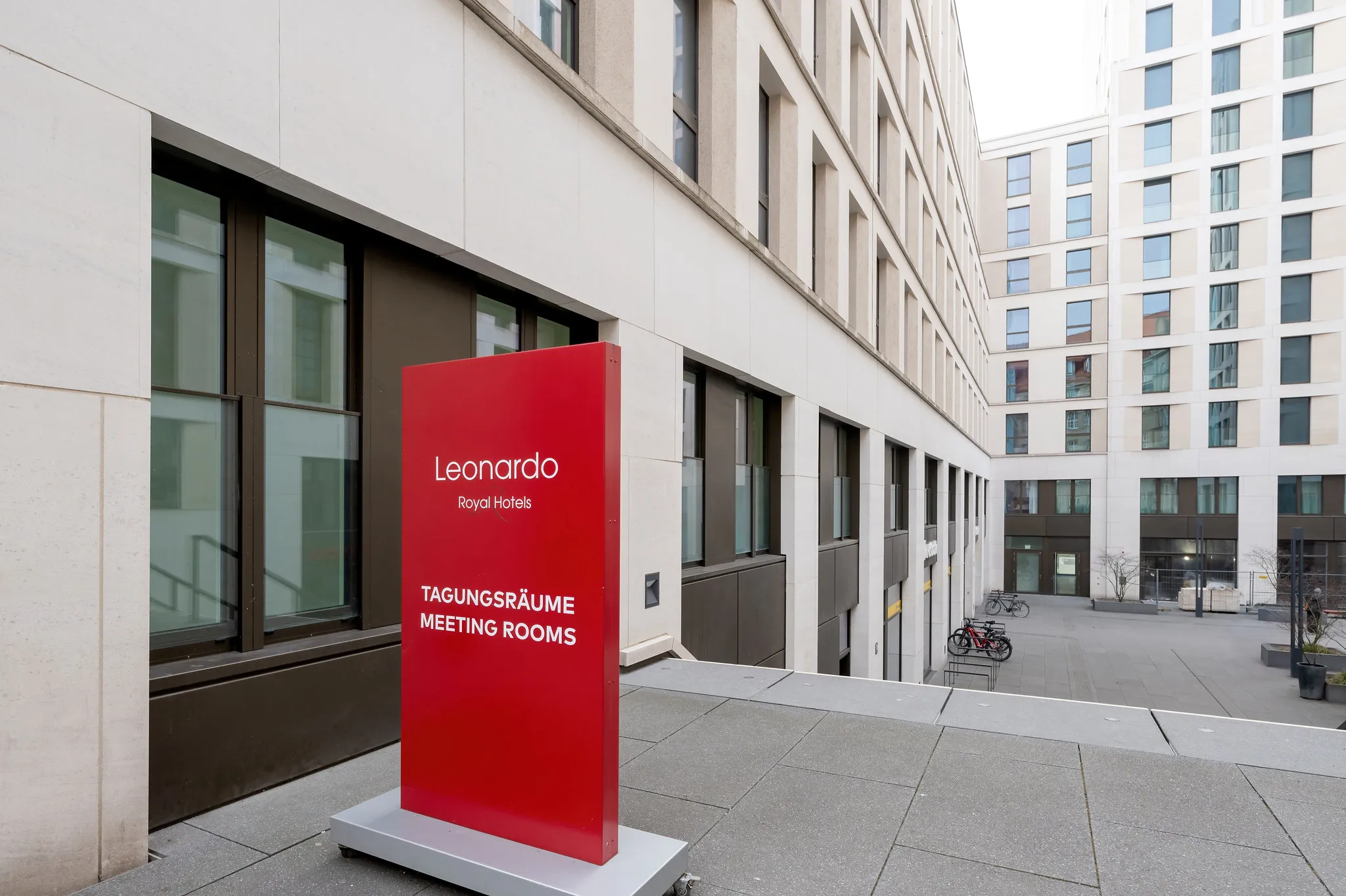Leonardo Royal Hotel Innenhof mit rotem Tagungsräume-Schild und moderner Hotelarchitektur