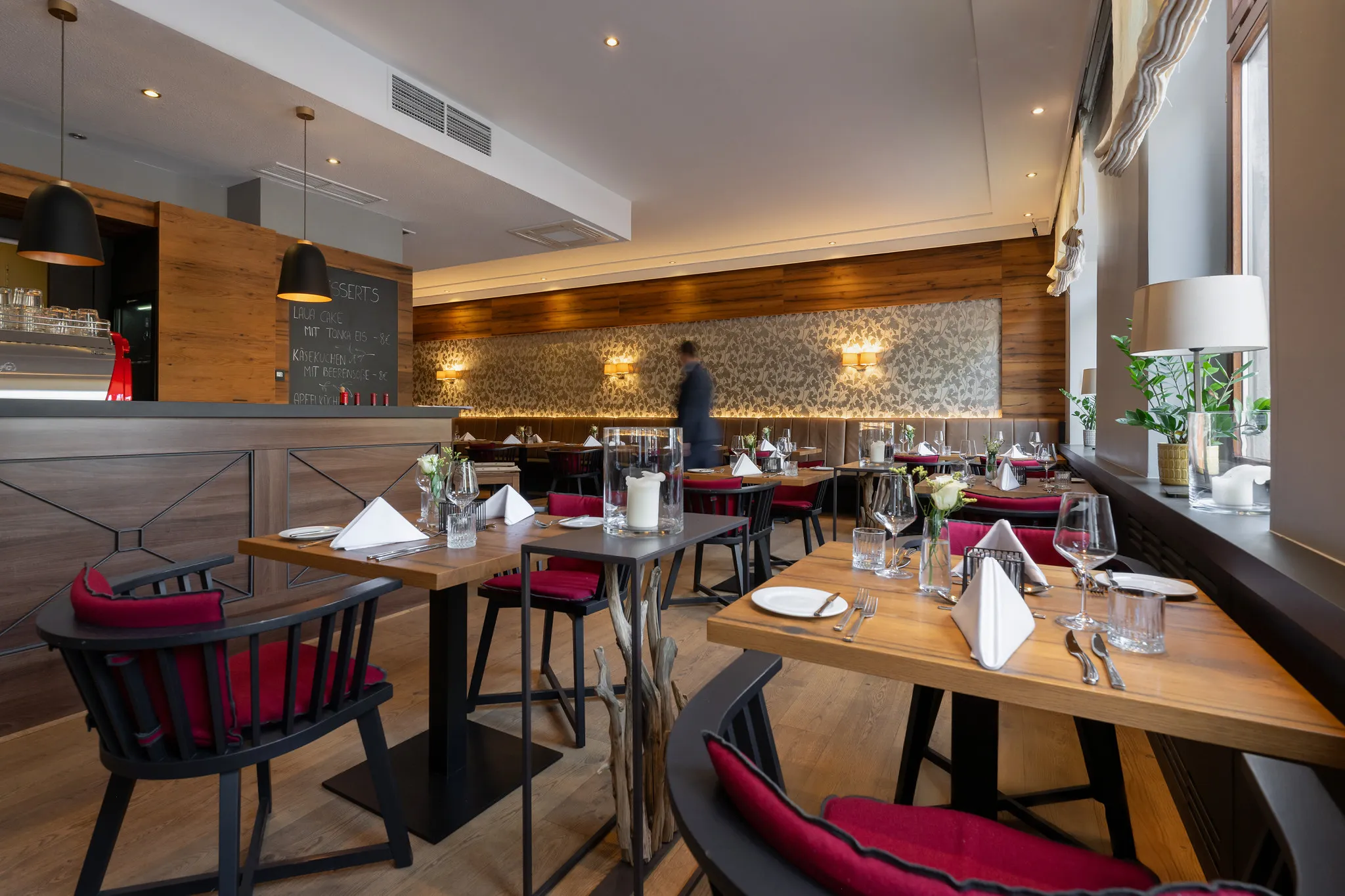 Modernes Hotelrestaurant mit Holzwänden, roten Stühlen und Kreidetafel für die Tageskarte