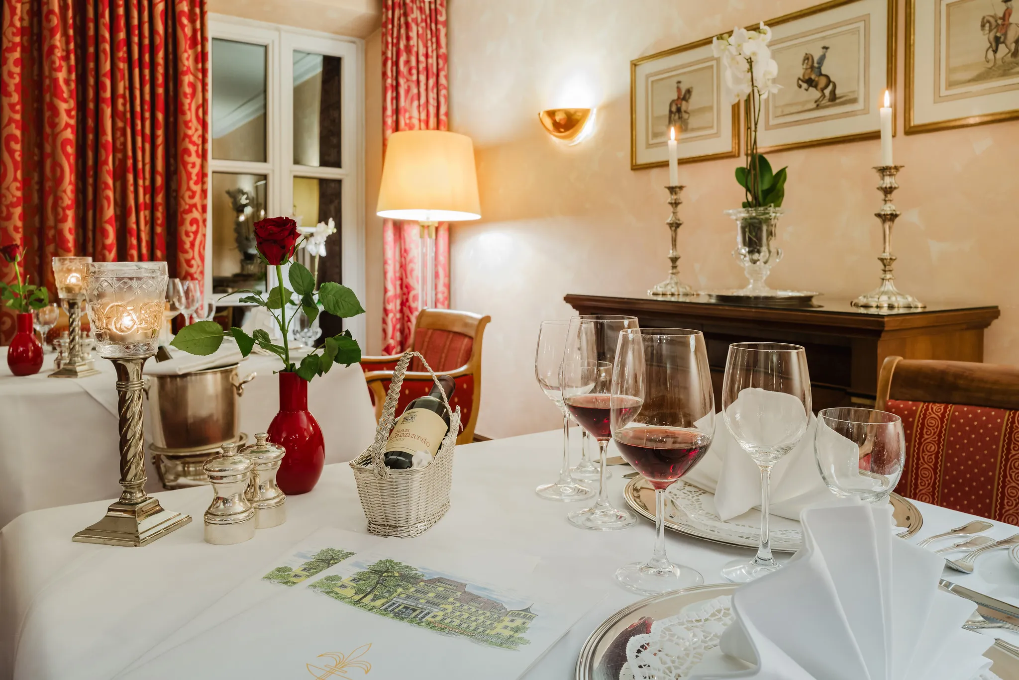 Nahaufnahme eines gedeckten Restauranttisches mit roter Rose, Kerzen und Weingläsern