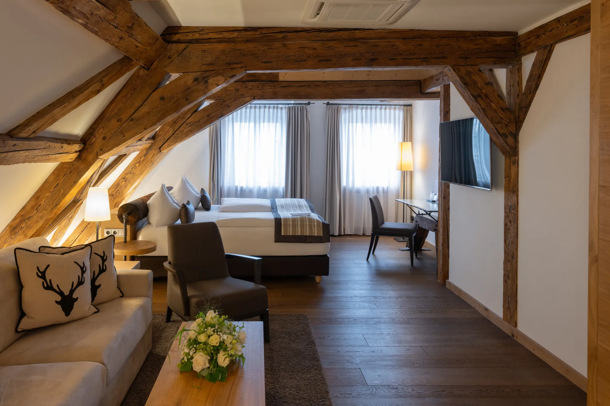 Geräumige Hotel-Suite mit historischen Holzbalken, Doppelbett und gemütlicher Sitzecke