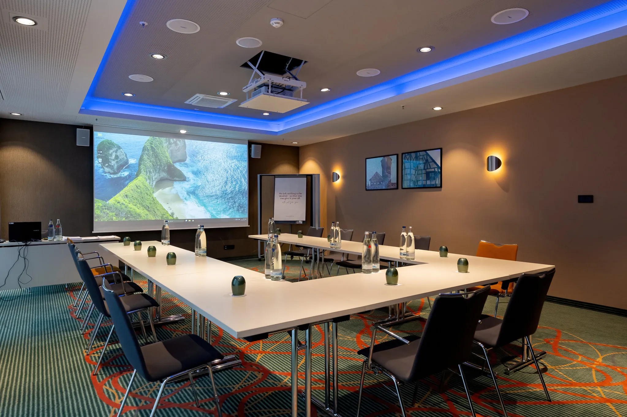 Moderner Hoteltagungsraum mit Beamer-Projektion, U-förmiger Bestuhlung und blauem LED-Ambientelicht