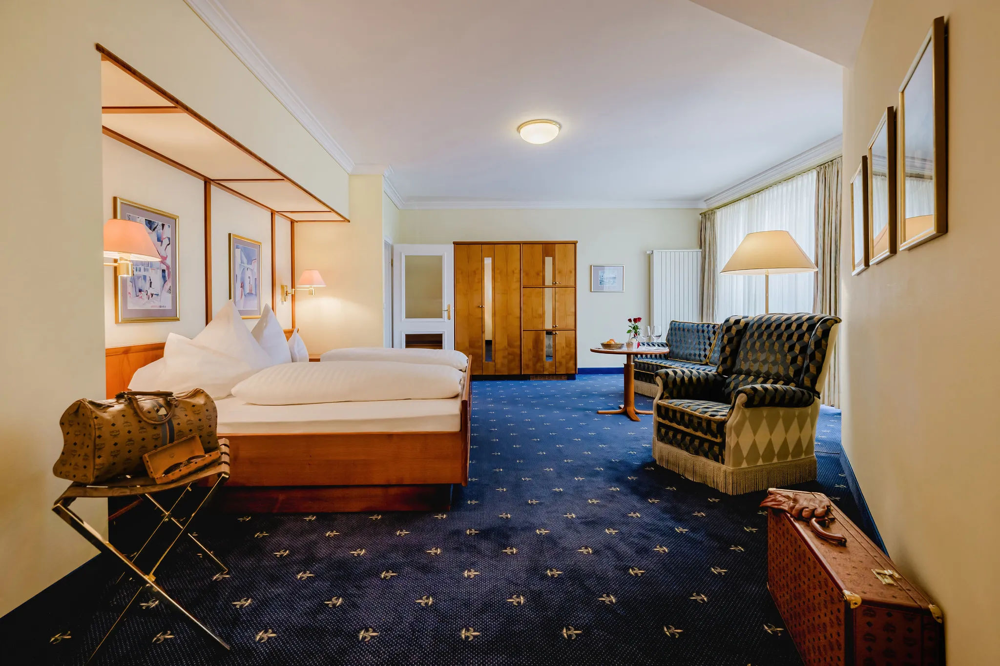 Klassisches Hotelzimmer mit Himmelbettrahmen, blauem Teppich und gemütlicher Sitzecke