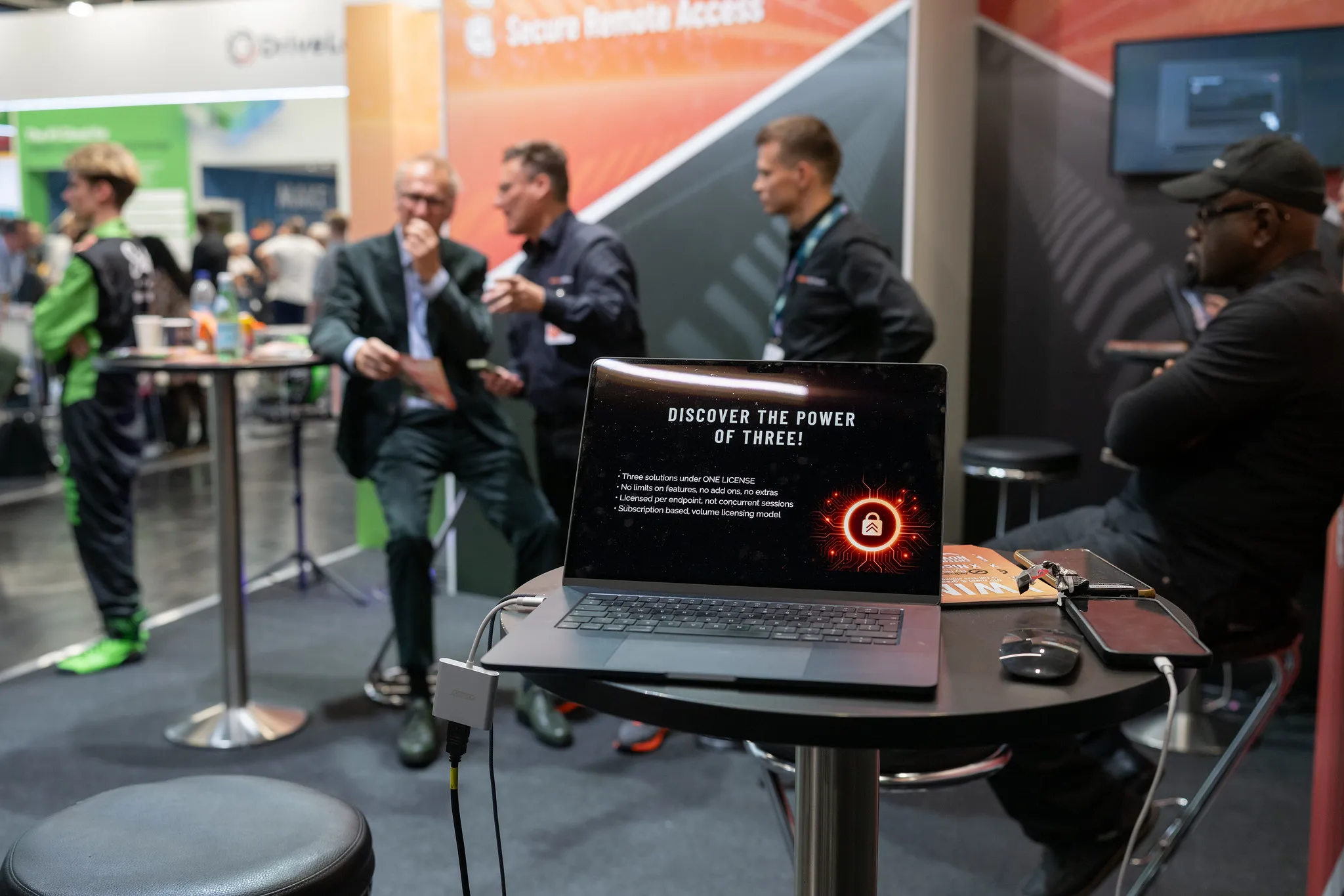 Laptop-Präsentation am IT-Sicherheitsstand auf der it-sa Nürnberg, Fachgespräche im Hintergrund.