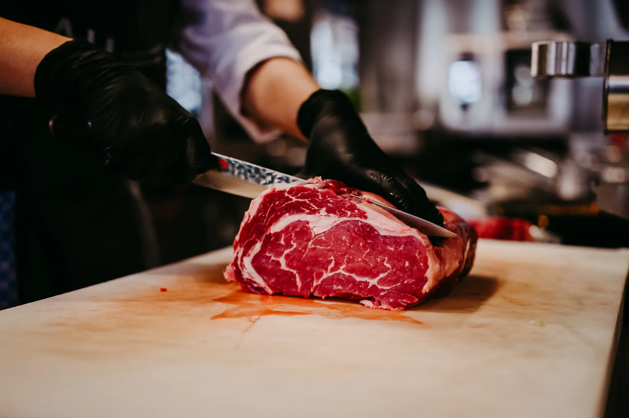 Koch schneidet ein großes rohes Rindersteak zu, Live-Küchenfotografie.