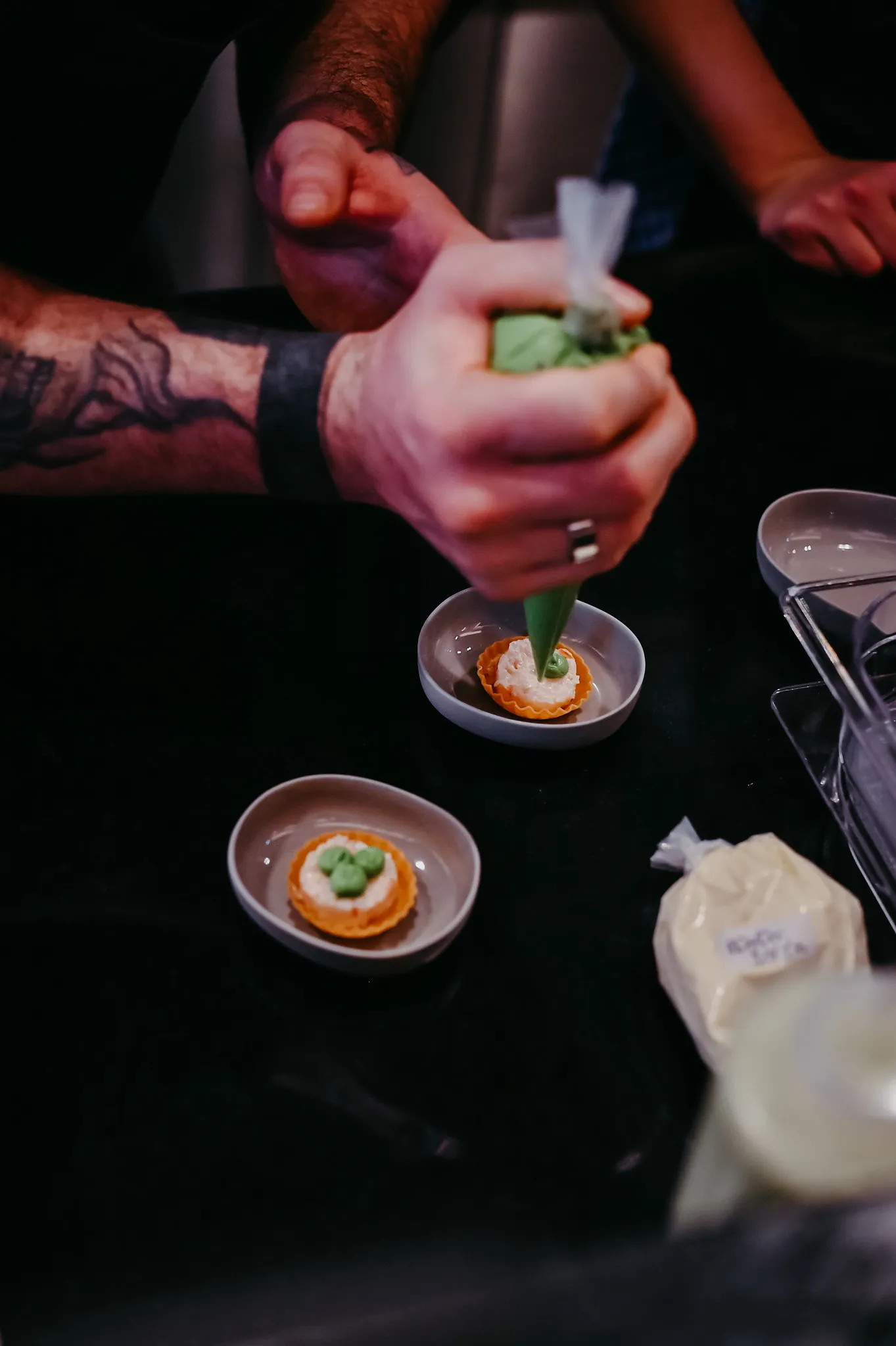 Koch füllt Tartelettes mit grüner Avocadocreme aus dem Spritzbeutel.