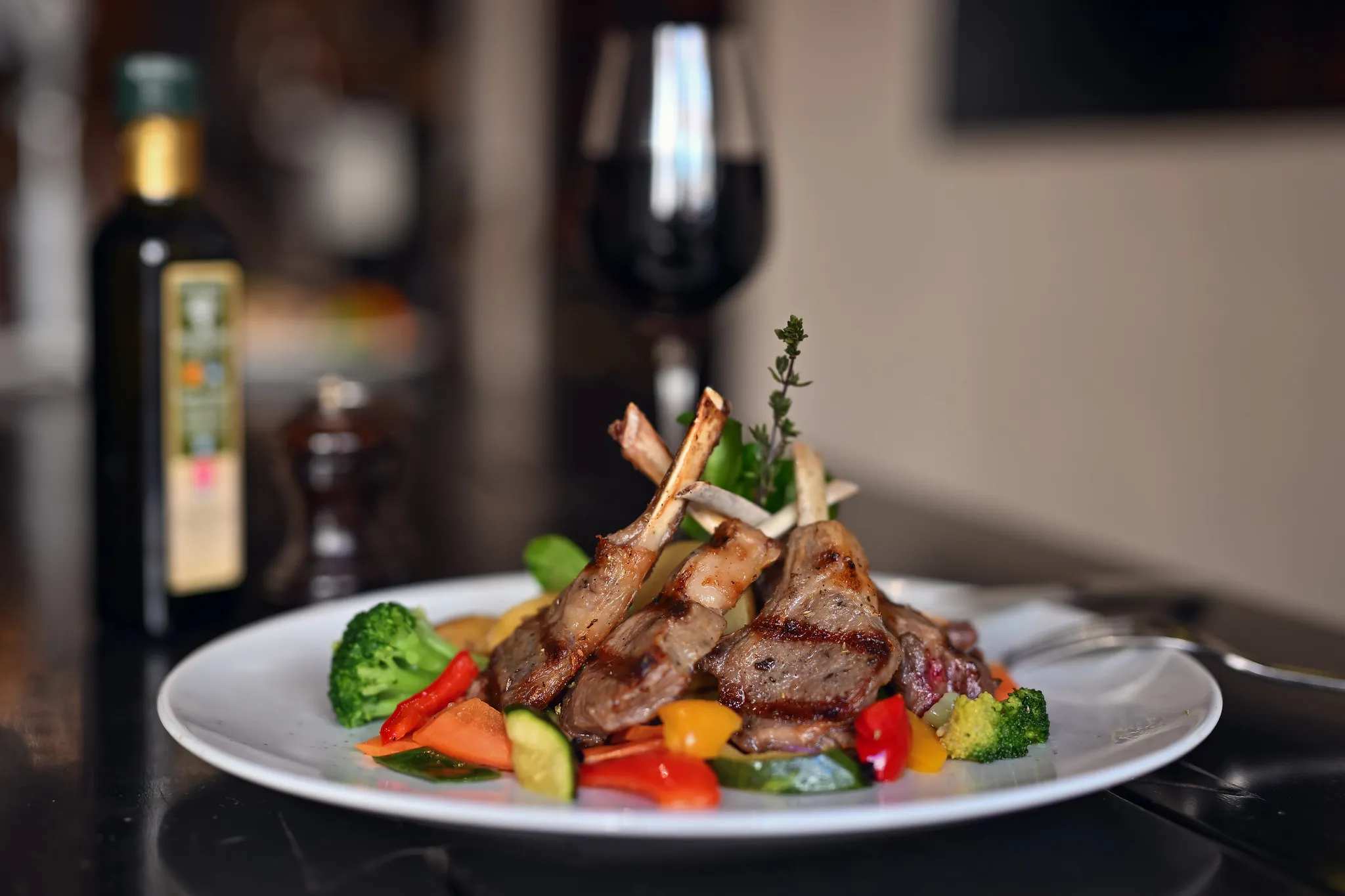 Gegrillte Lammkoteletts mit buntem Gemüse und Rotwein, mediterrane Food-Fotografie.