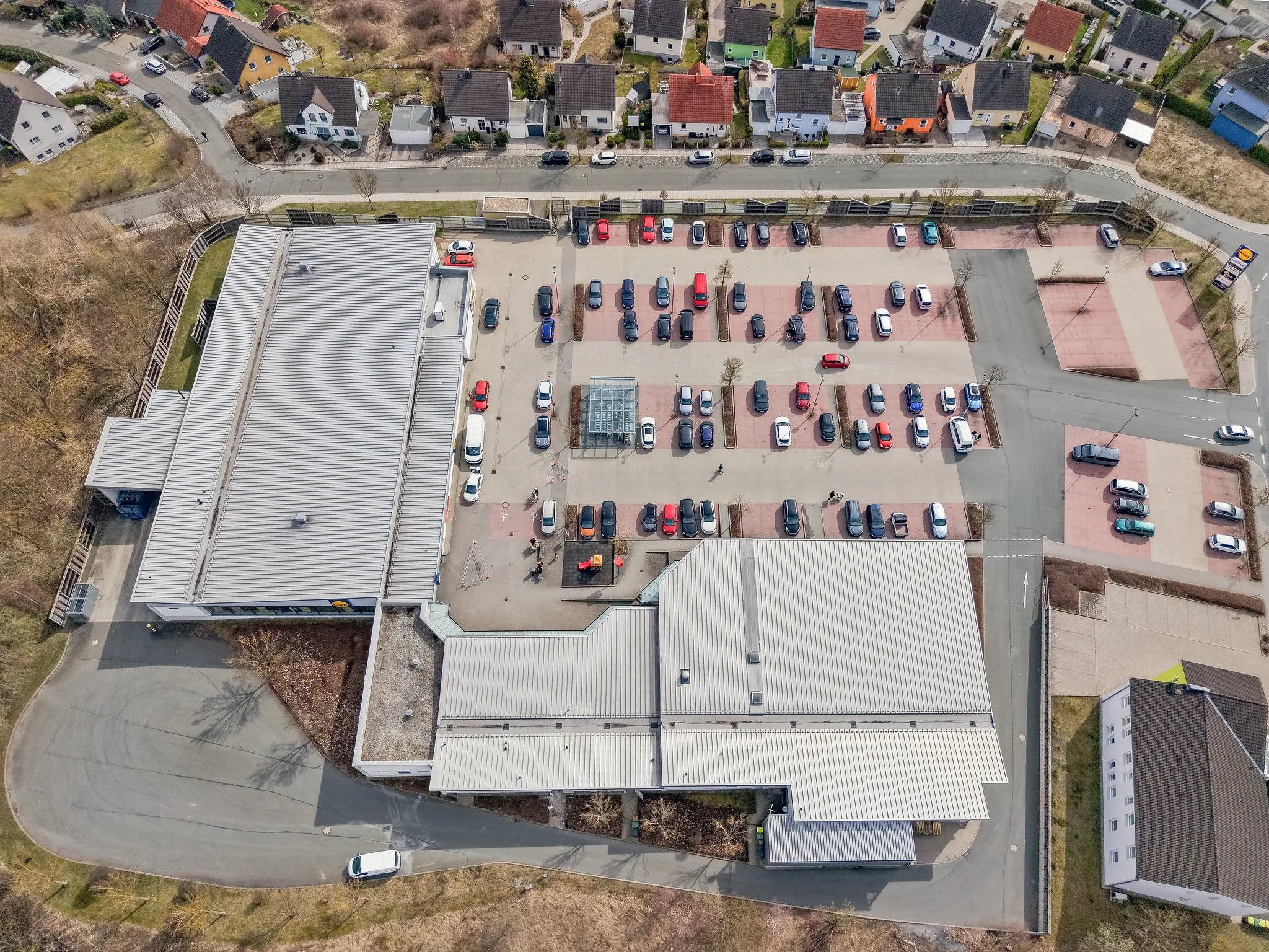 Drohnenaufnahme eines Lidl-Markts mit Parkplatz und Spielplatz von oben