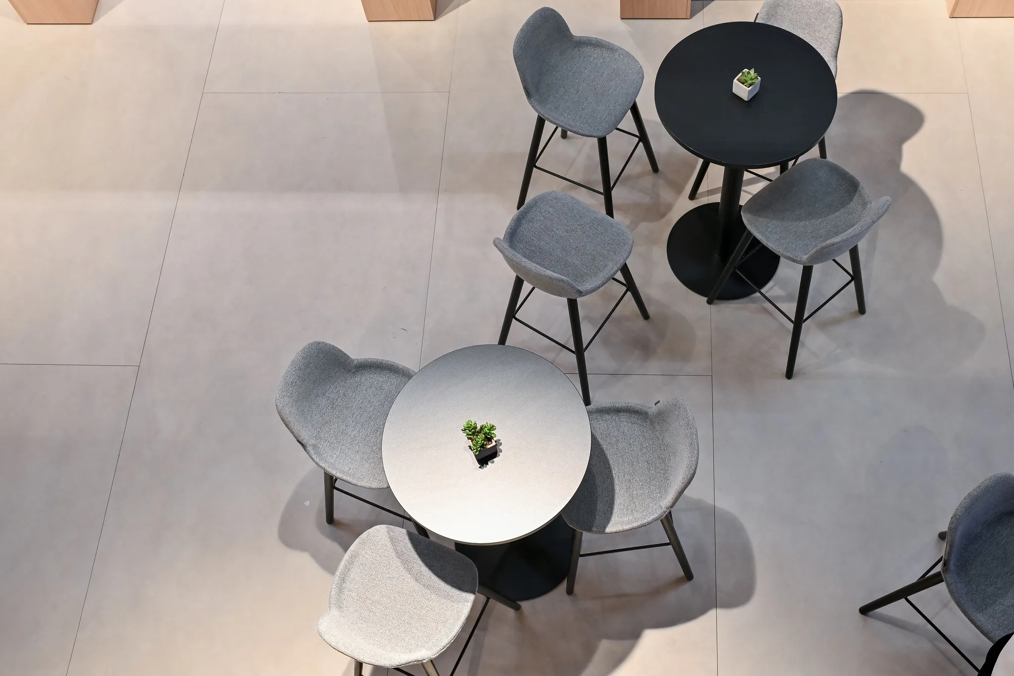Lounge-Bereich am Messestand von oben, runde Tische und graue Stühle in eleganter Anordnung.