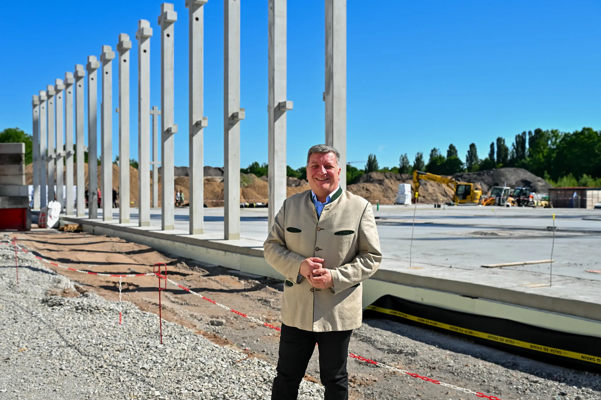 Bauherr im Trachtenjanker vor Betonfertigteilen der UTN-Baustelle