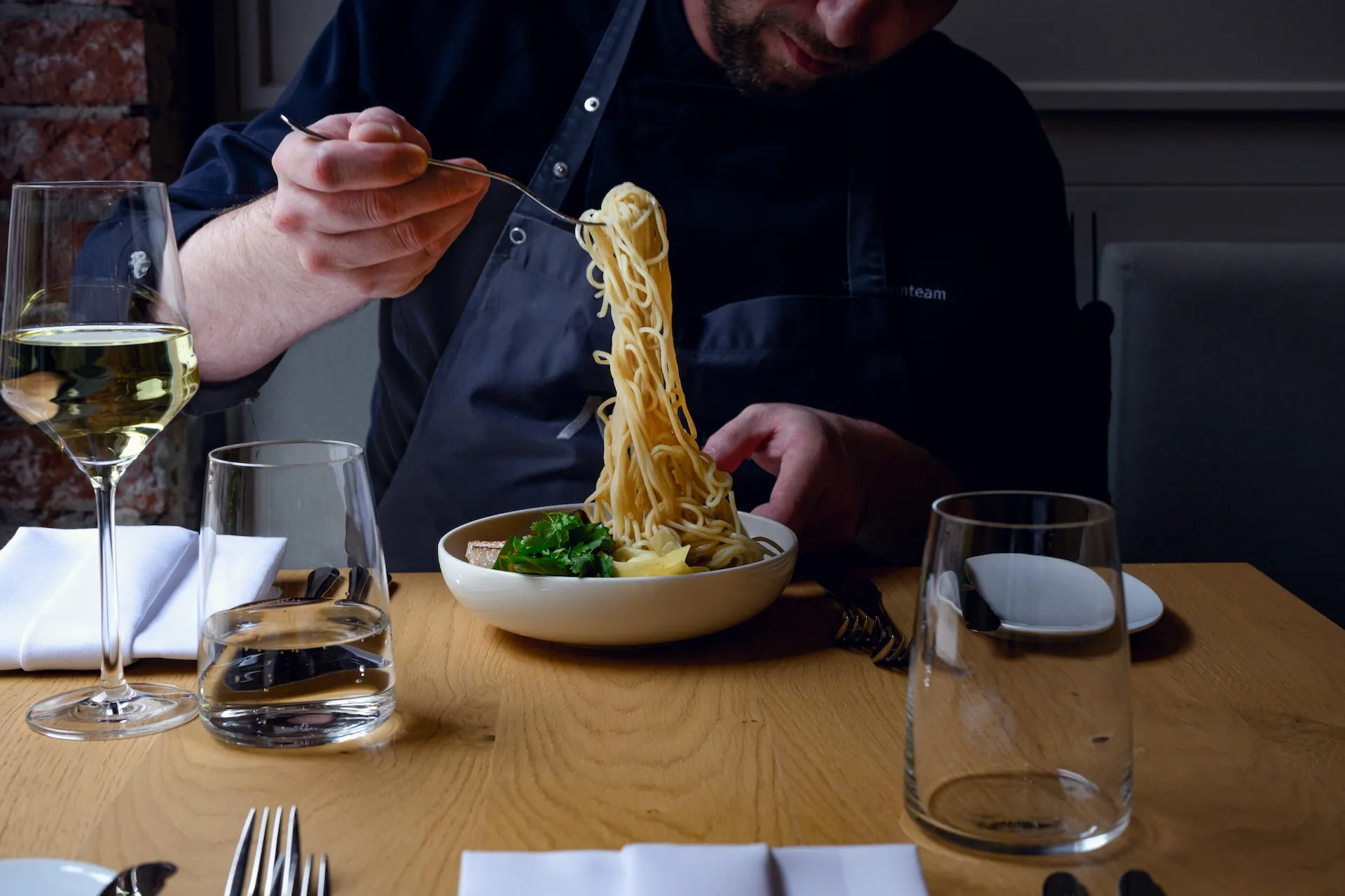 Mann isst Nudeln mit Glas Wein – Genussmoment eingefangen.