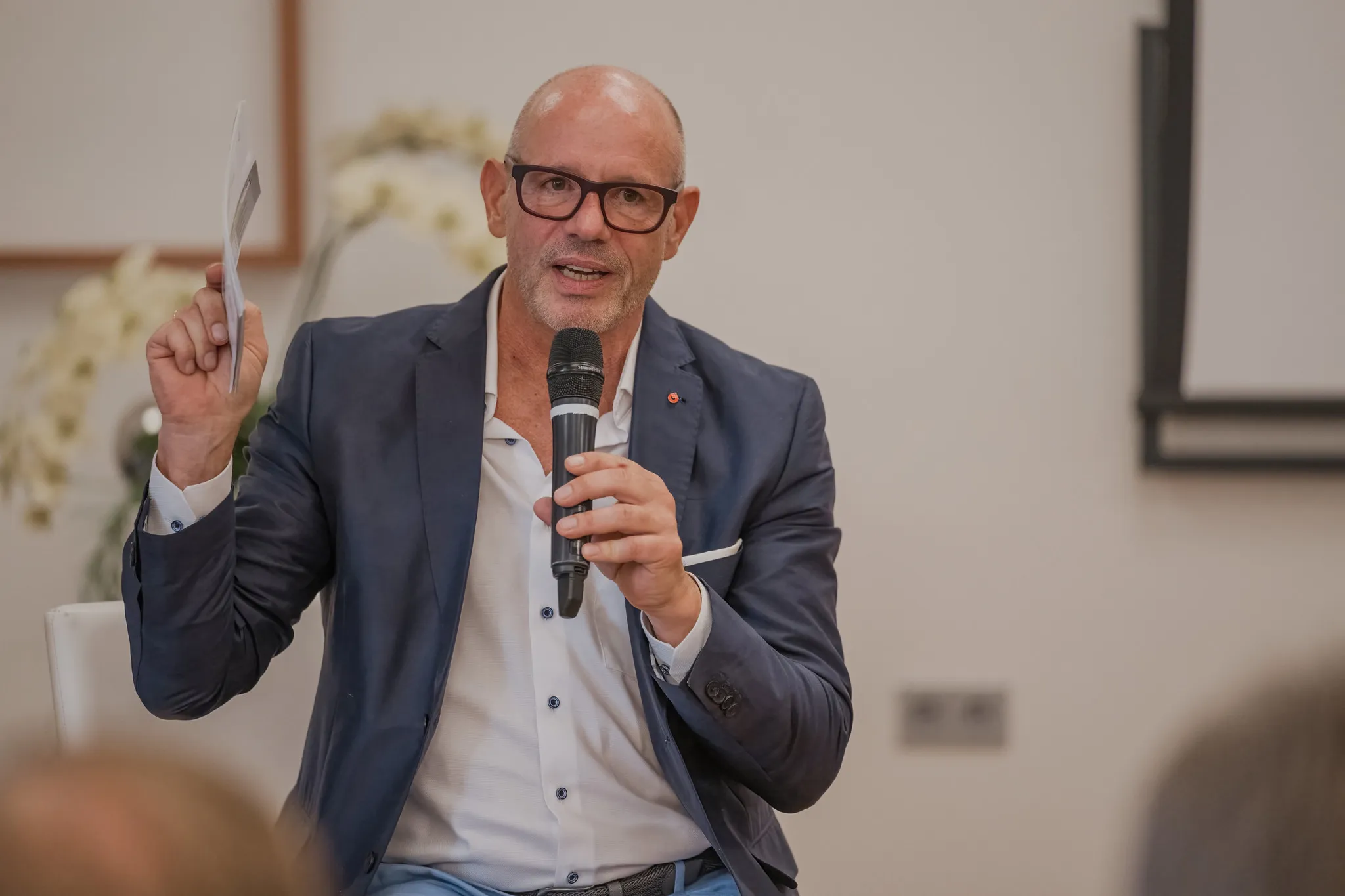 Mann mit Brille hält einen Vortrag mit Mikrofon, dynamisches Business-Portrait