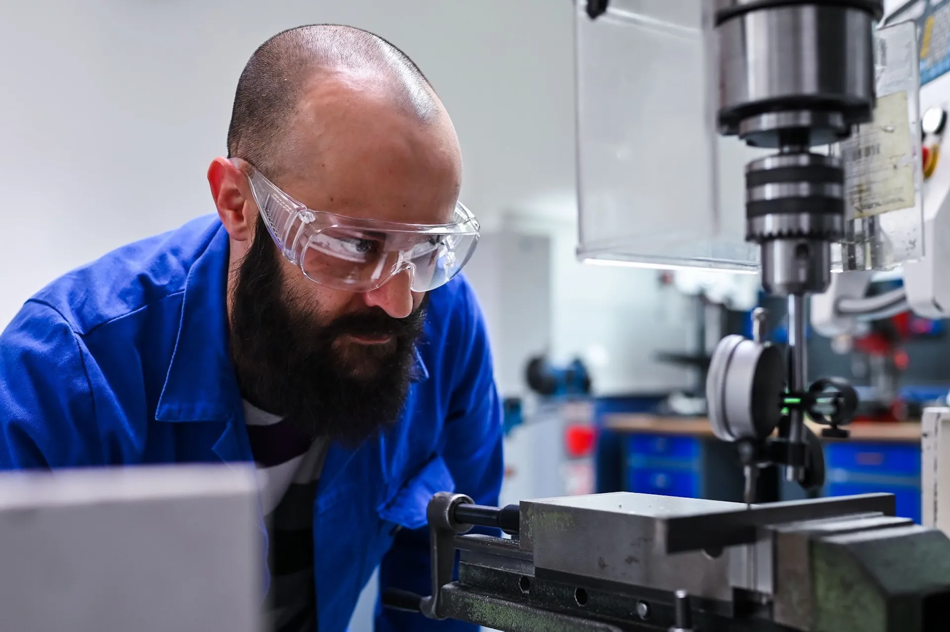 Mitarbeiter bedient eine Bohrmaschine mit Schutzbrille, authentische Industriefotografie in Nürnberg.