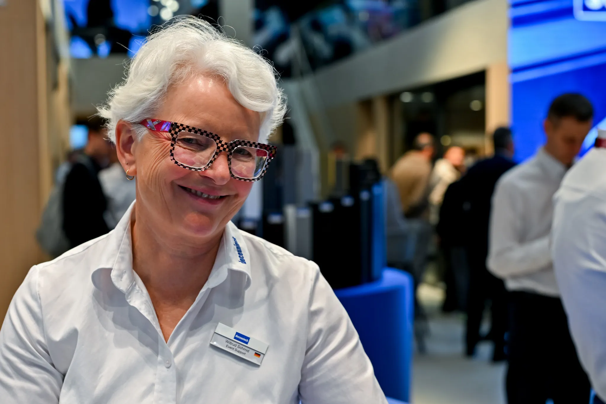 Portrait einer lächelnden Messemitarbeiterin mit auffälliger Brille am Deceuninck-Stand in Nürnberg.