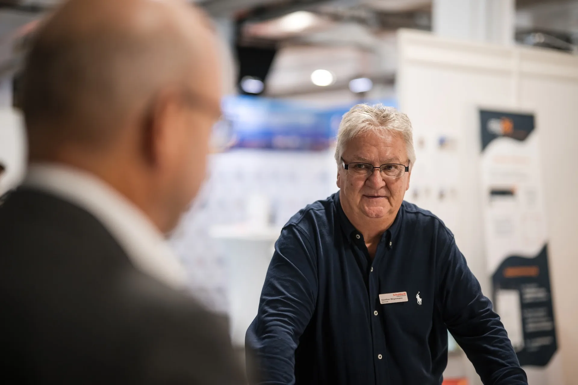 Two men in trade fair conversation, authentically captured.