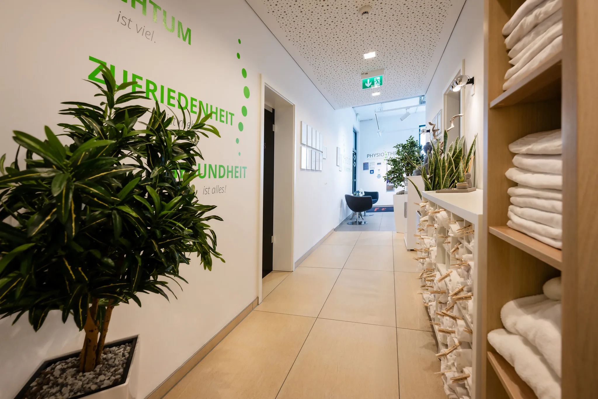 Physiotherapie-Empfangsbereich mit Handtuchregal und Pflanzen.