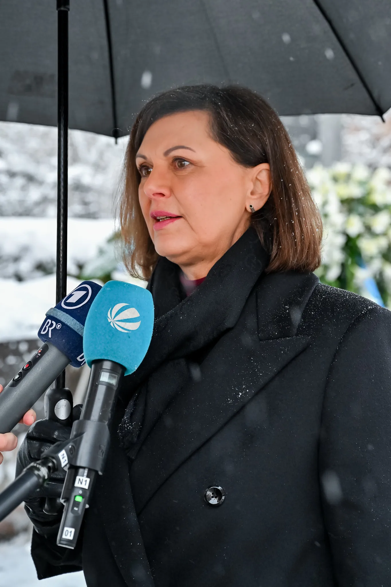 Politikerin gibt Statement an BR und ARD Mikrofone bei Gedenkveranstaltung
