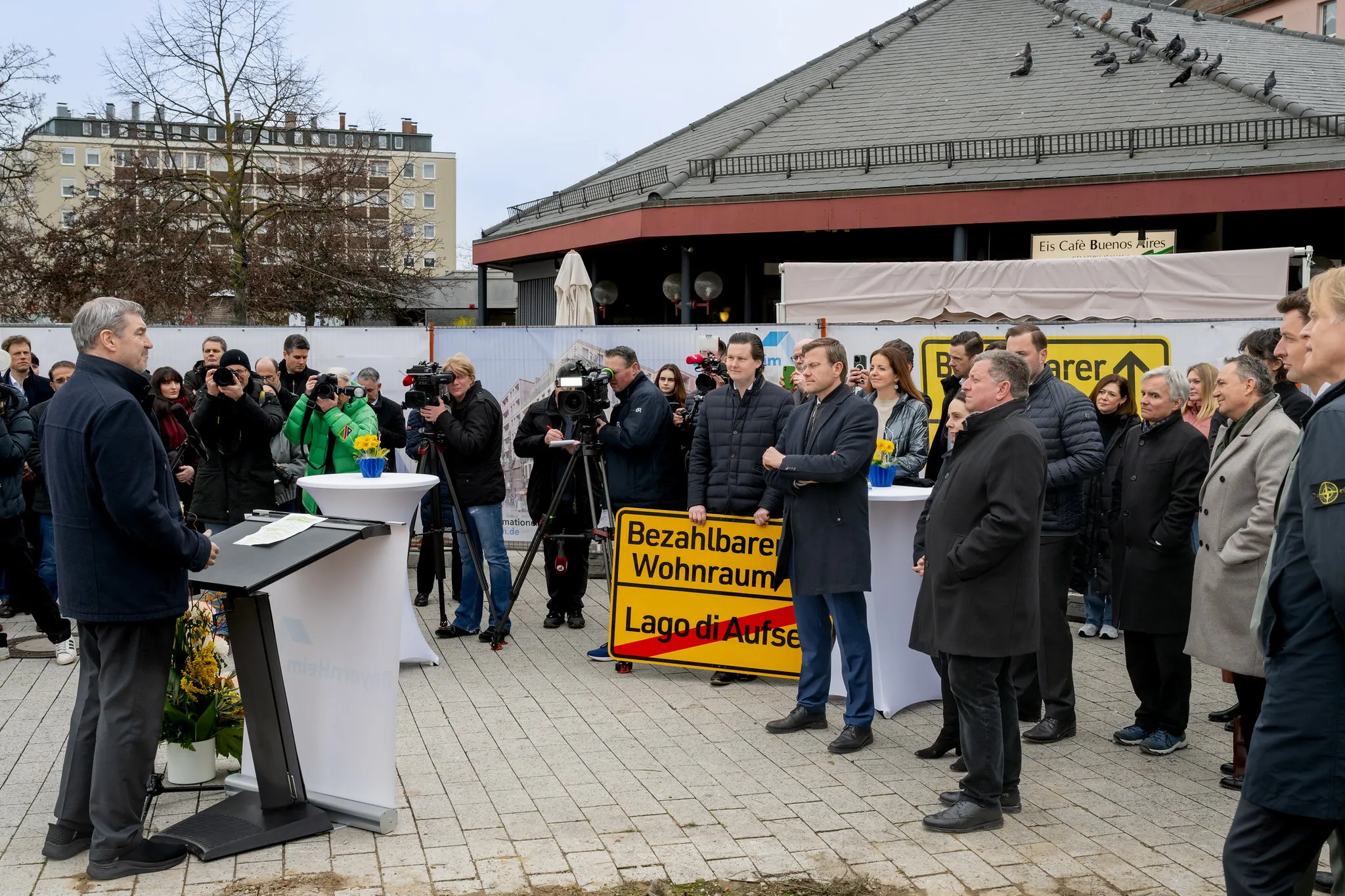 Pressetermin: Redner am Pult, Schild Bezahlbarer Wohnraum, Politiker und Medienvertreter