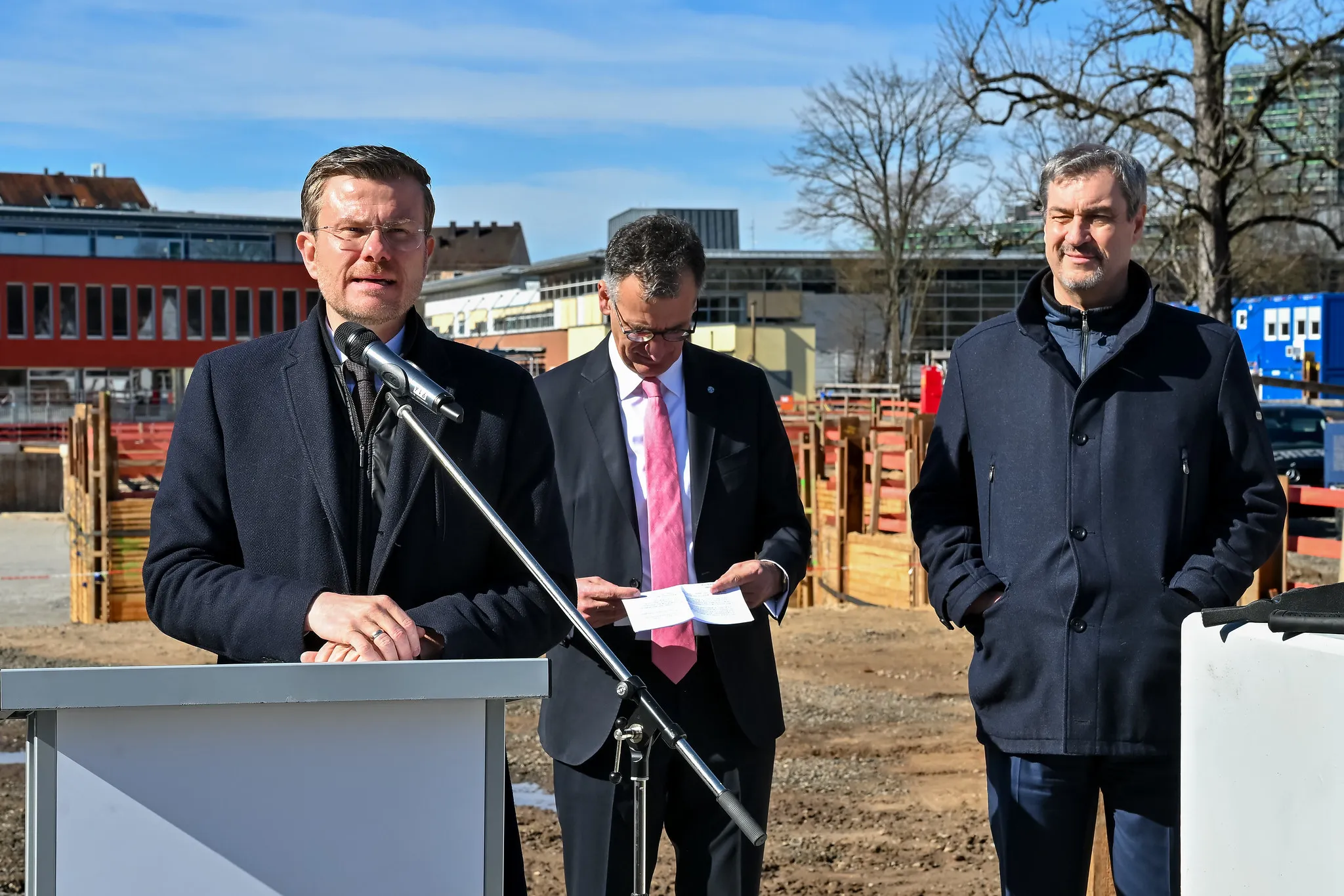 Rede am Rednerpult bei feierlicher Grundsteinlegung auf der Baustelle