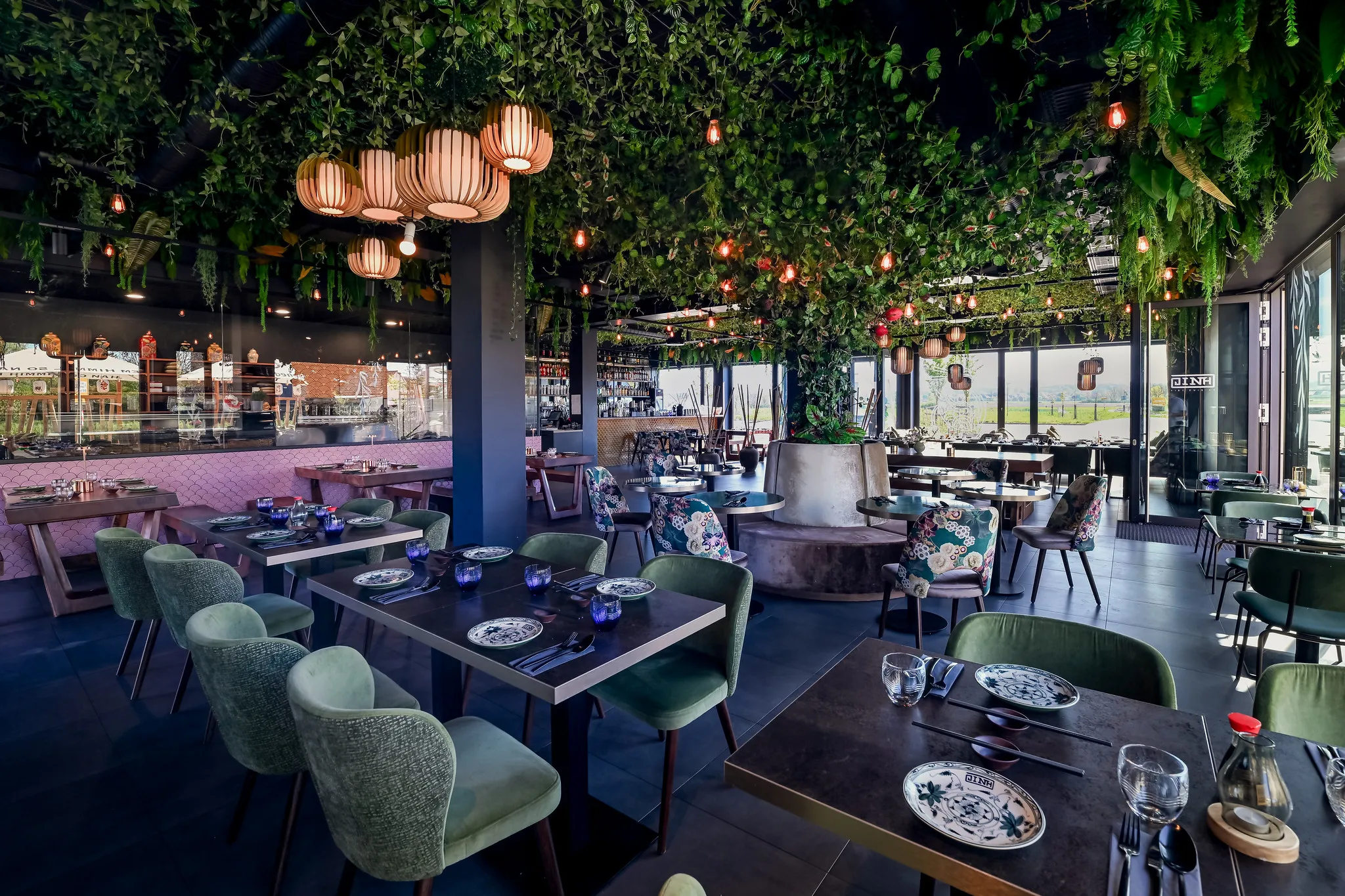 Eingedeckter Gastraum mit begrünter Decke, Lampions und Fensterfront, Restaurantfotografie Nürnberg.