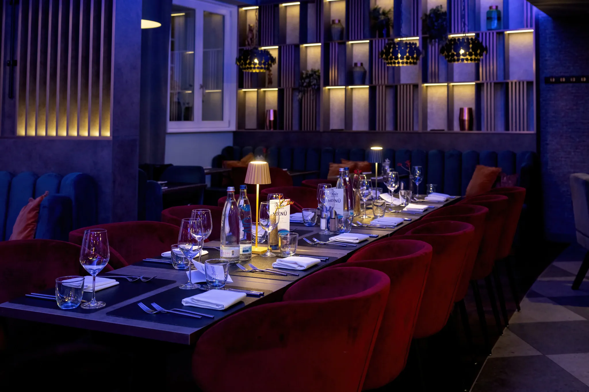 Restaurant mit roten Samtstühlen und blauem Ambientelicht.