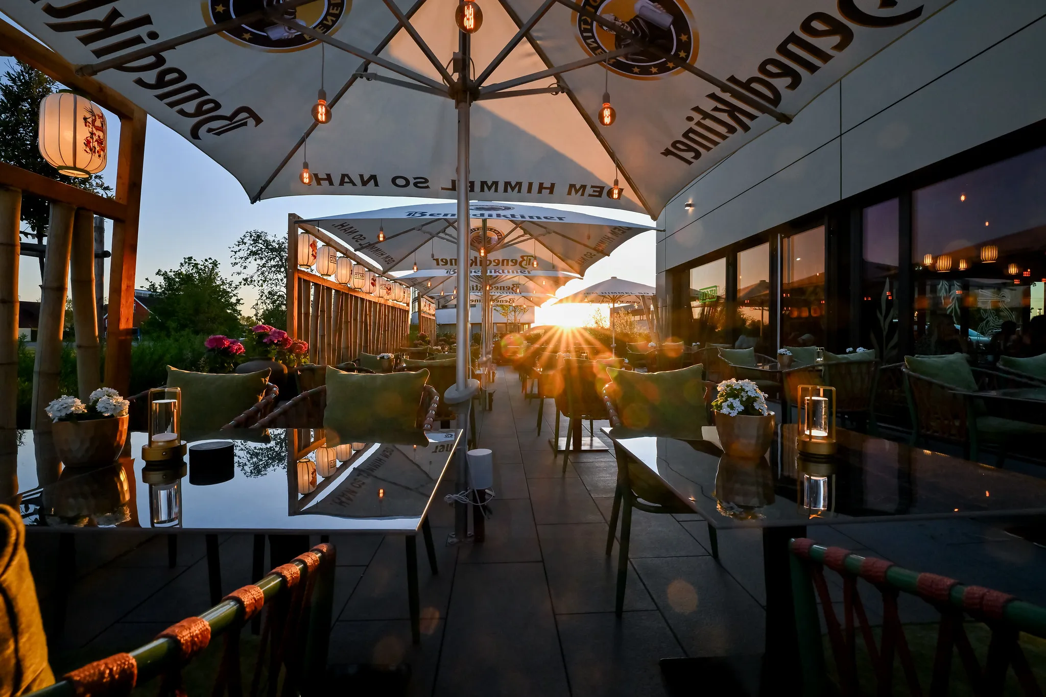 Restaurantterrasse mit Sonnenschirmen und Lampions im Sonnenuntergang, Gastronomie-Fotografie Nürnberg.