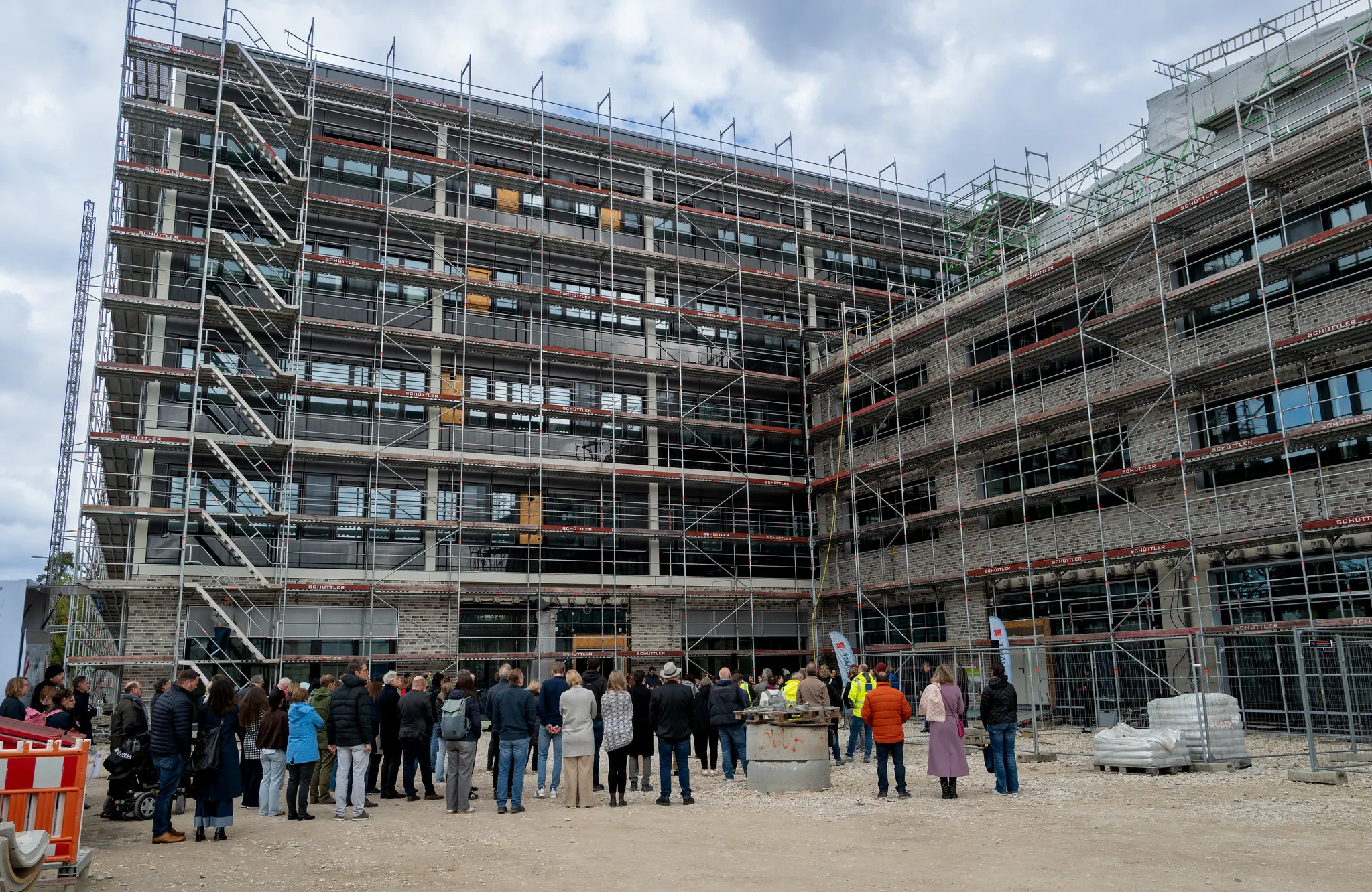 Menschenmenge beim Richtfest vor gerüstetem Bürogebäude