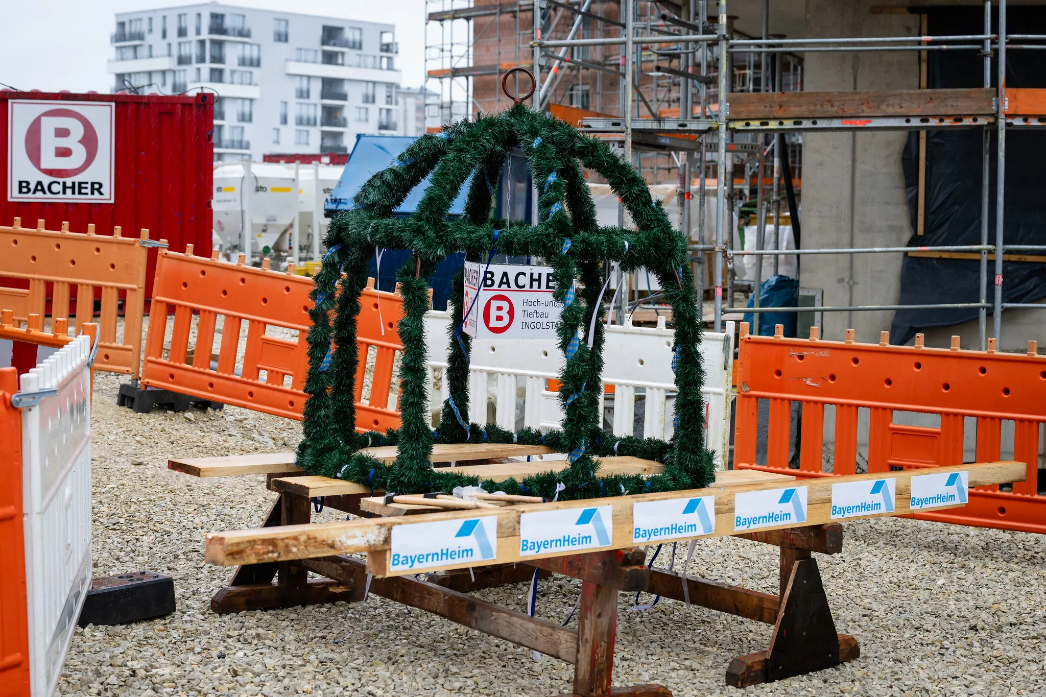 Richtkrone mit Tannenzweigen und Bändern vor BayernHeim-Baustelle