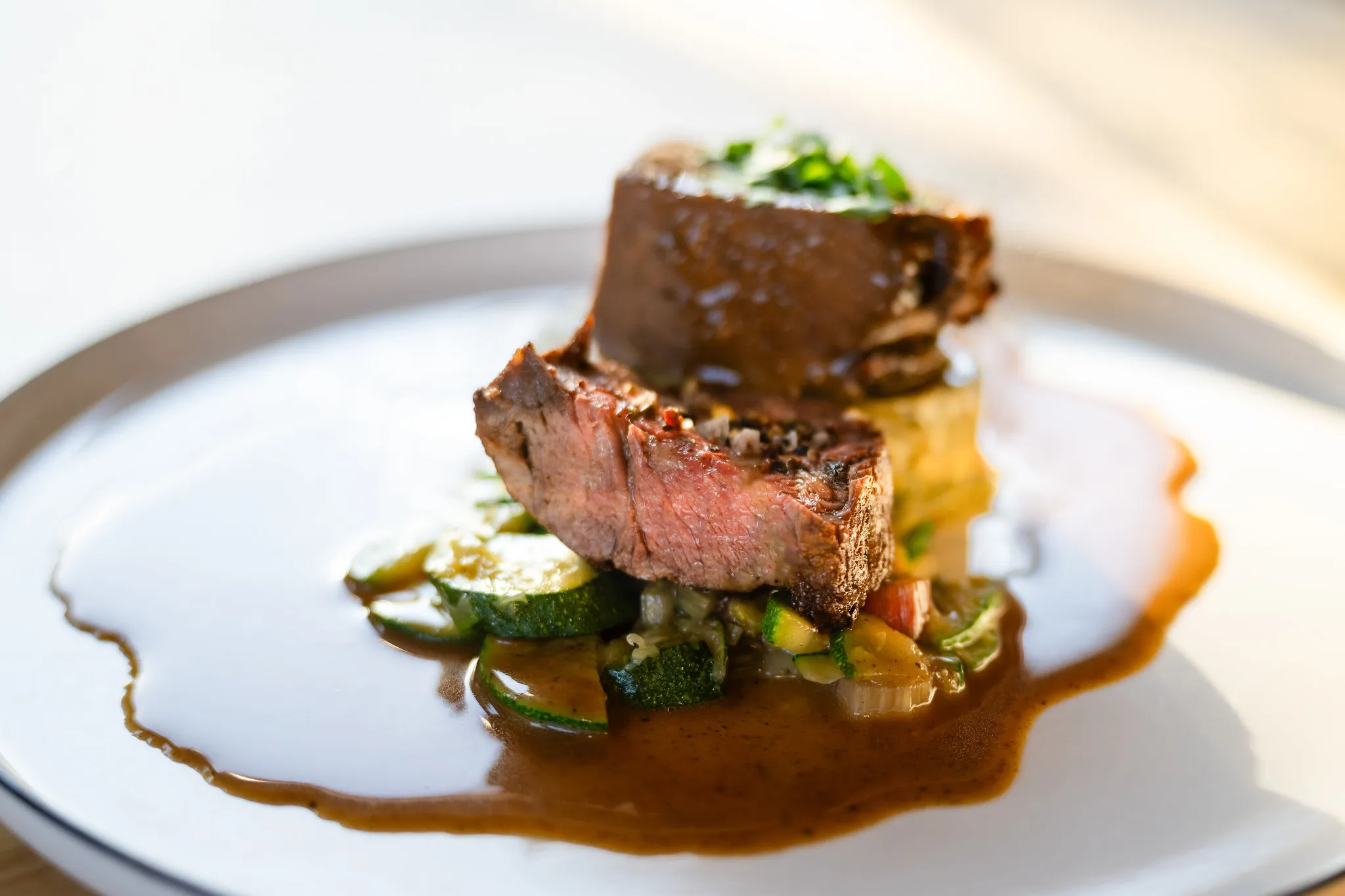 Gebratenes Rinderfilet mit Zucchini und Rotweinsoße, gehobene Gastronomie-Fotografie.