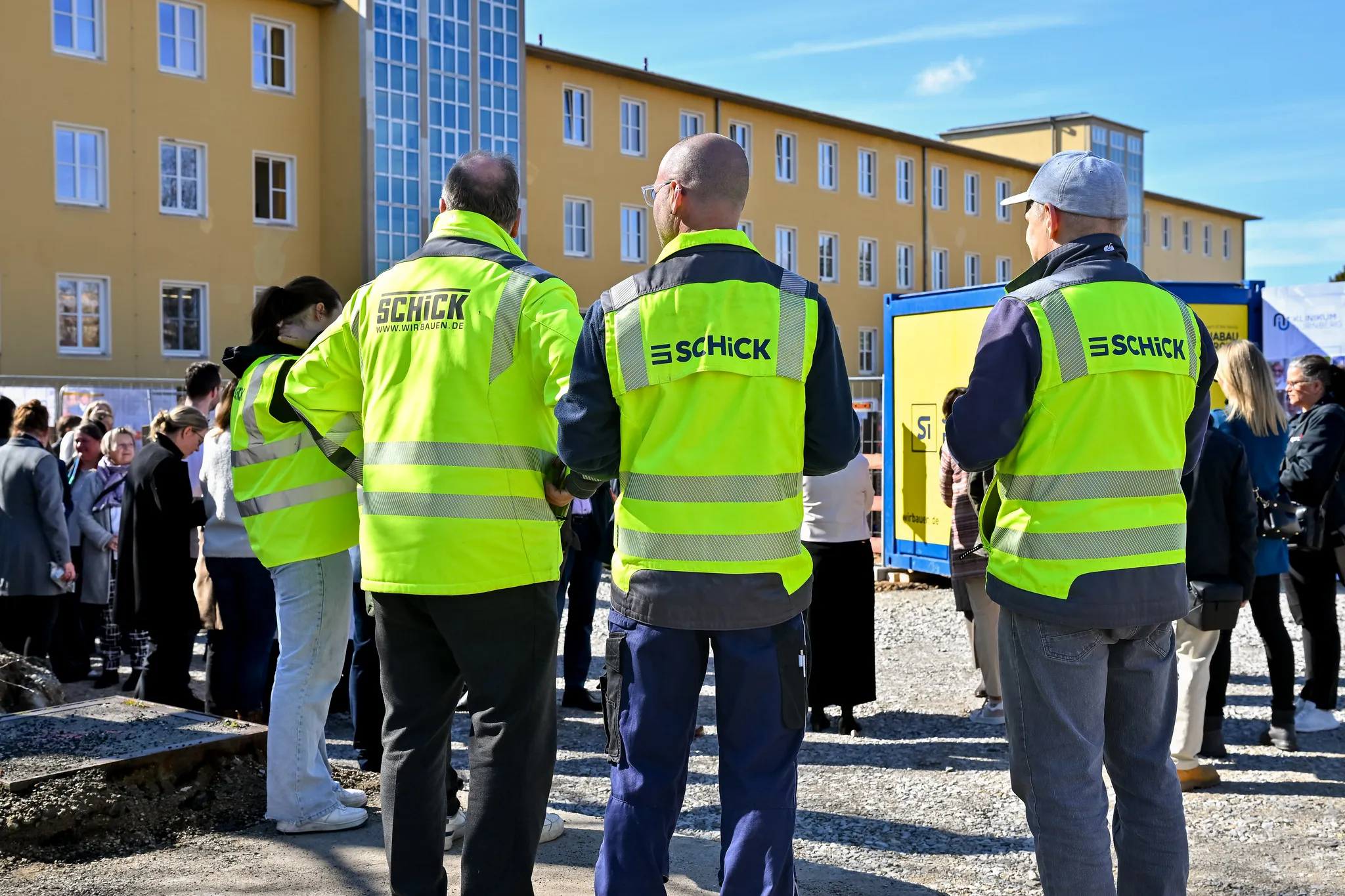 Schick-Bauarbeiter in gelben Warnwesten bei der Grundsteinlegung