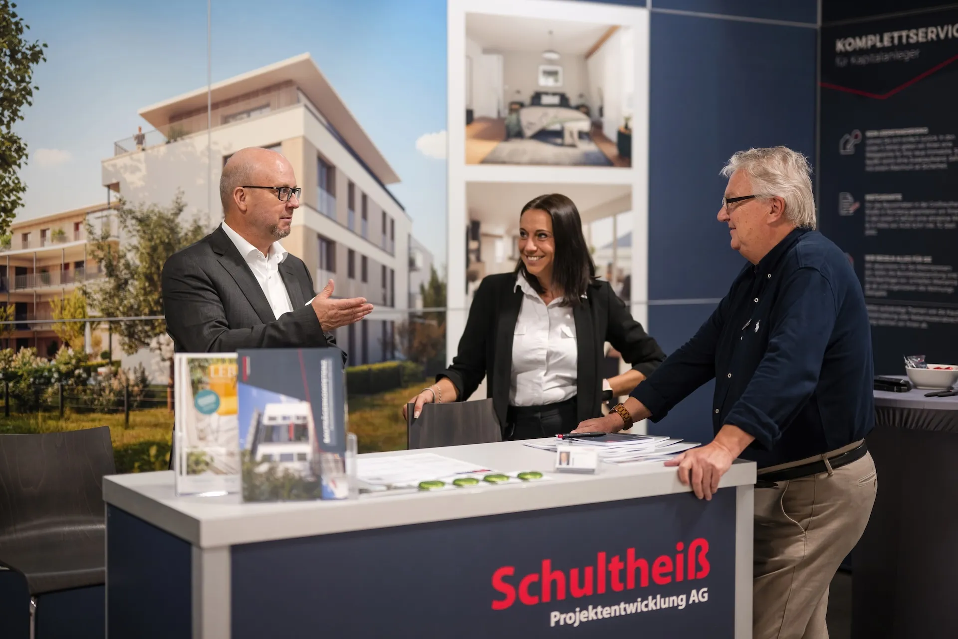 Three-way conversation at the trade fair booth, authentic, friendly, in the midst of the action.