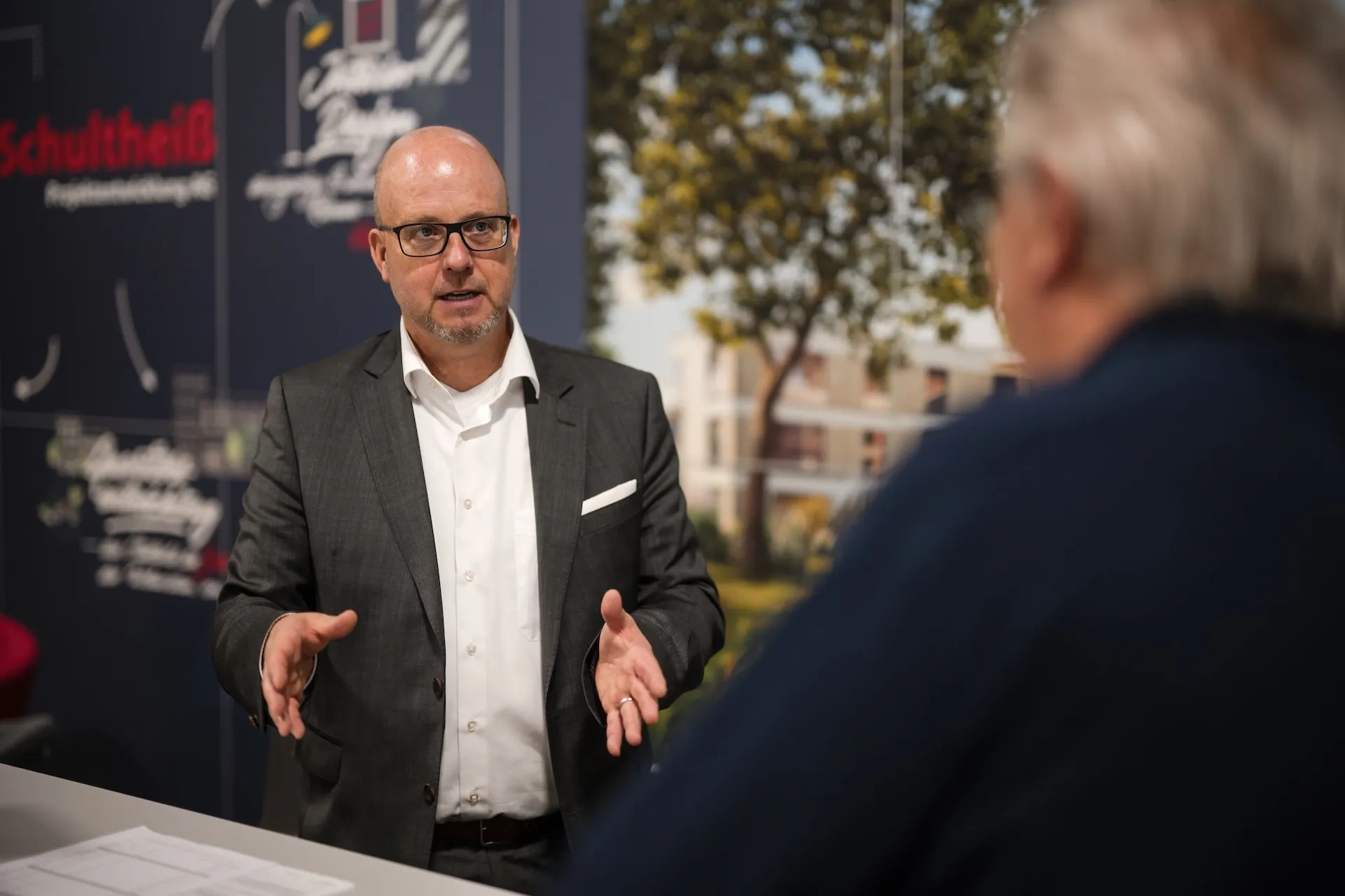 Trade fair conversation at the Schultheiss booth, proximity and dialogue in focus.