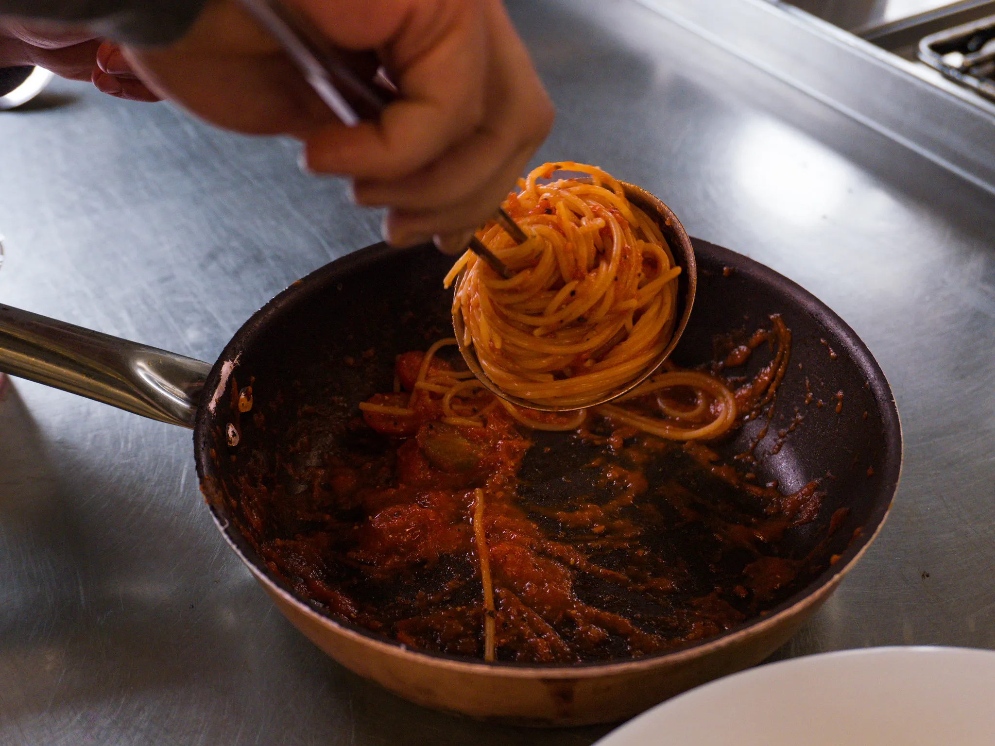 Spaghetti in Tomatensoße in der Kupferpfanne, Küchenmoment der Gastronomie.