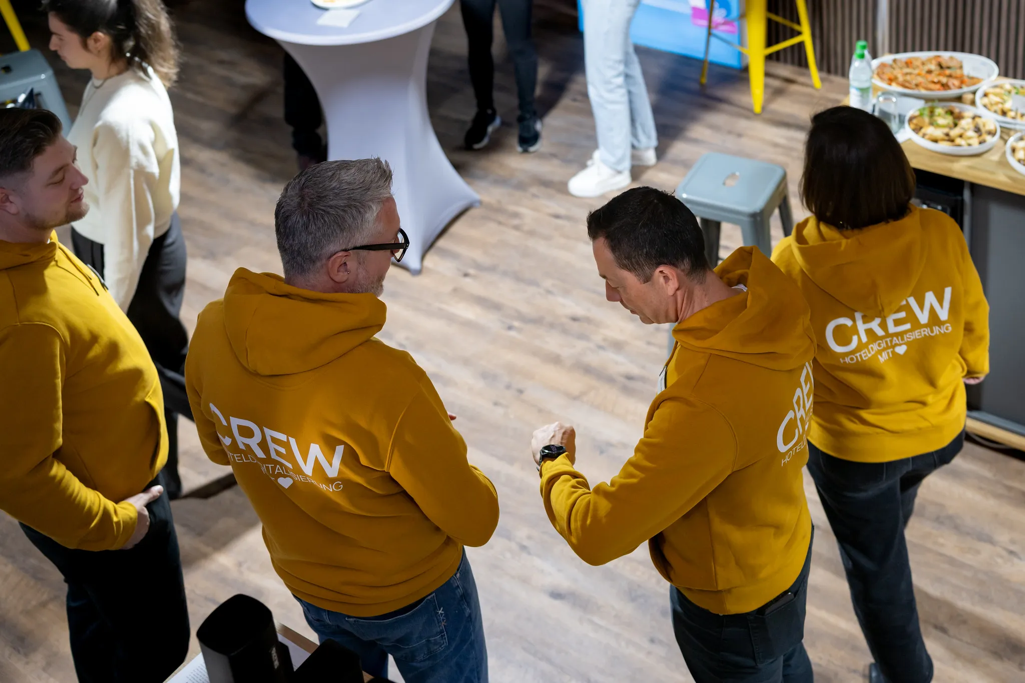 Team in gelben Crew-Hoodies vernetzt sich beim Firmenevent